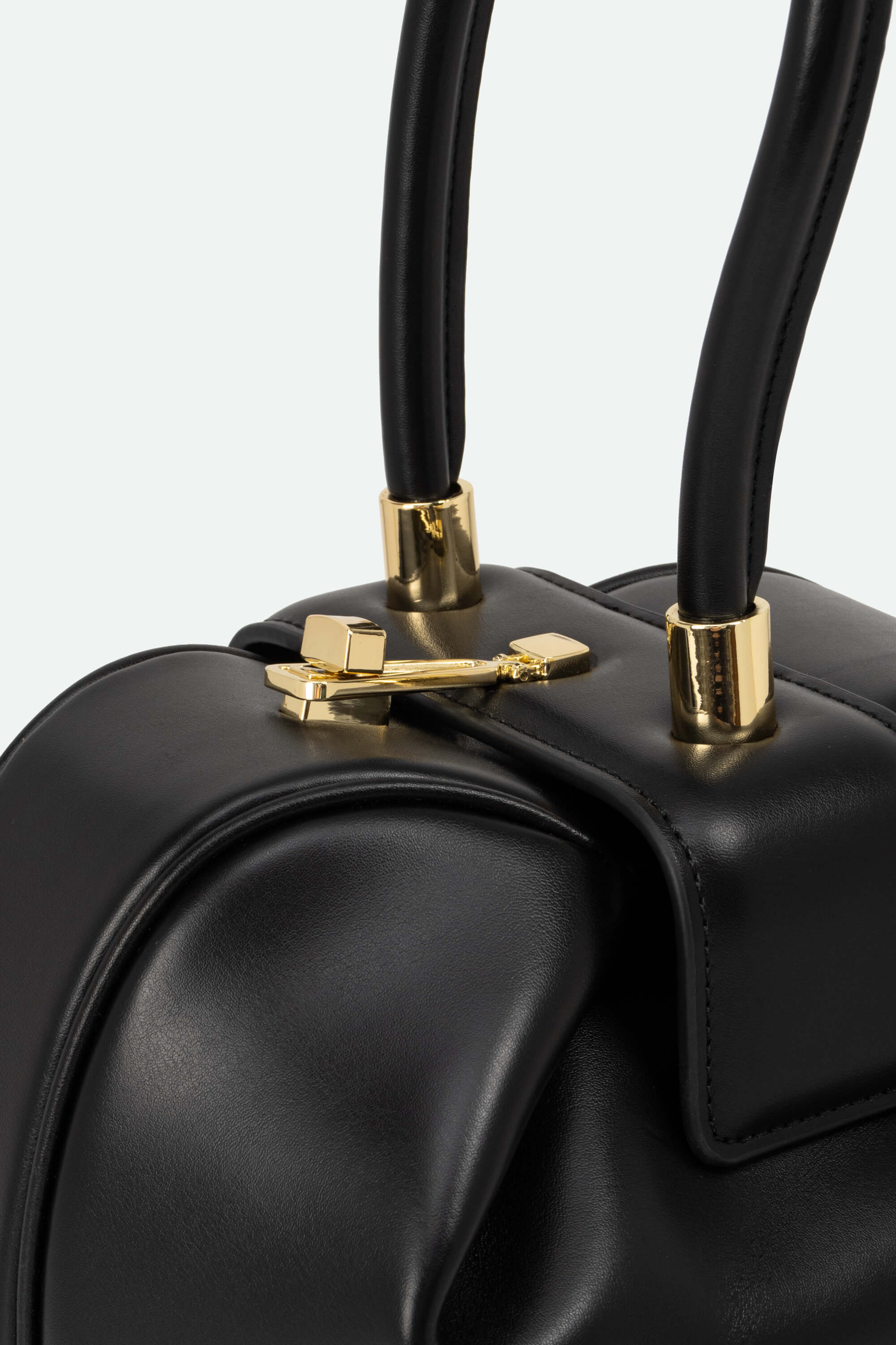 Black handbag with gold hardware on a light gray background