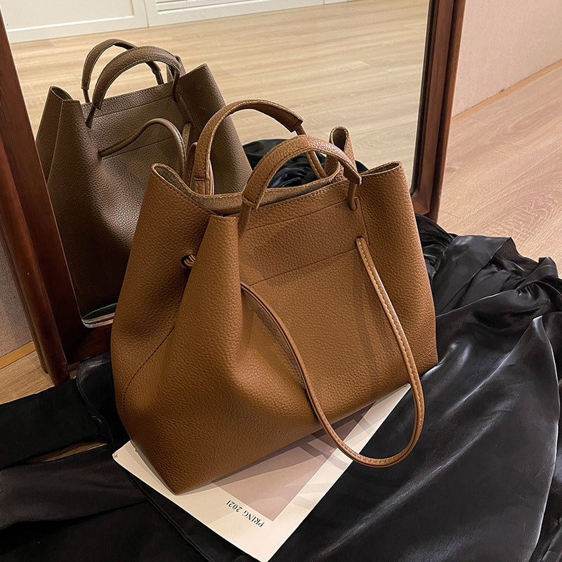 Brown leather handbag on a black surface with a mirror reflection.