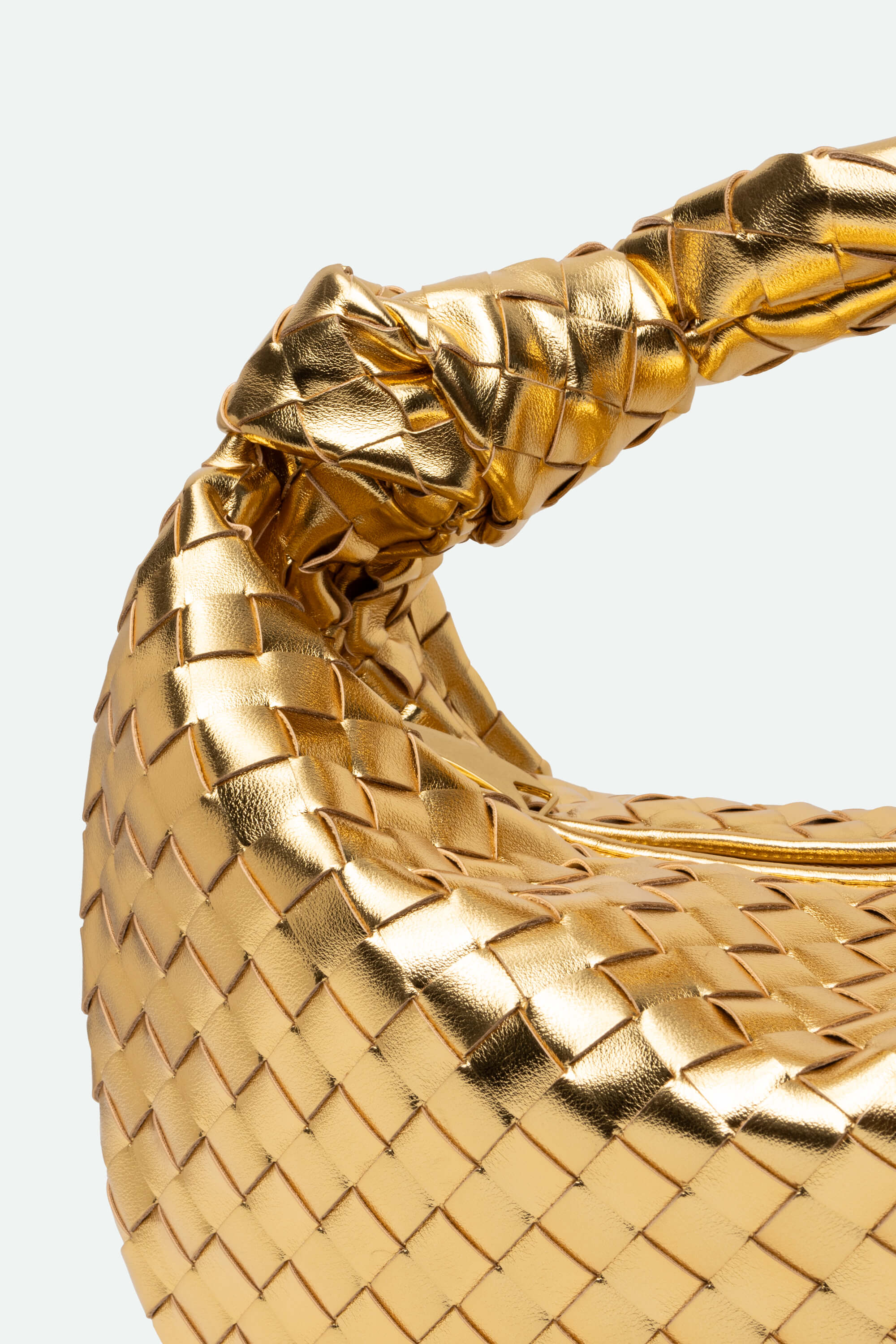 Close-up of a gold woven handbag on a white background