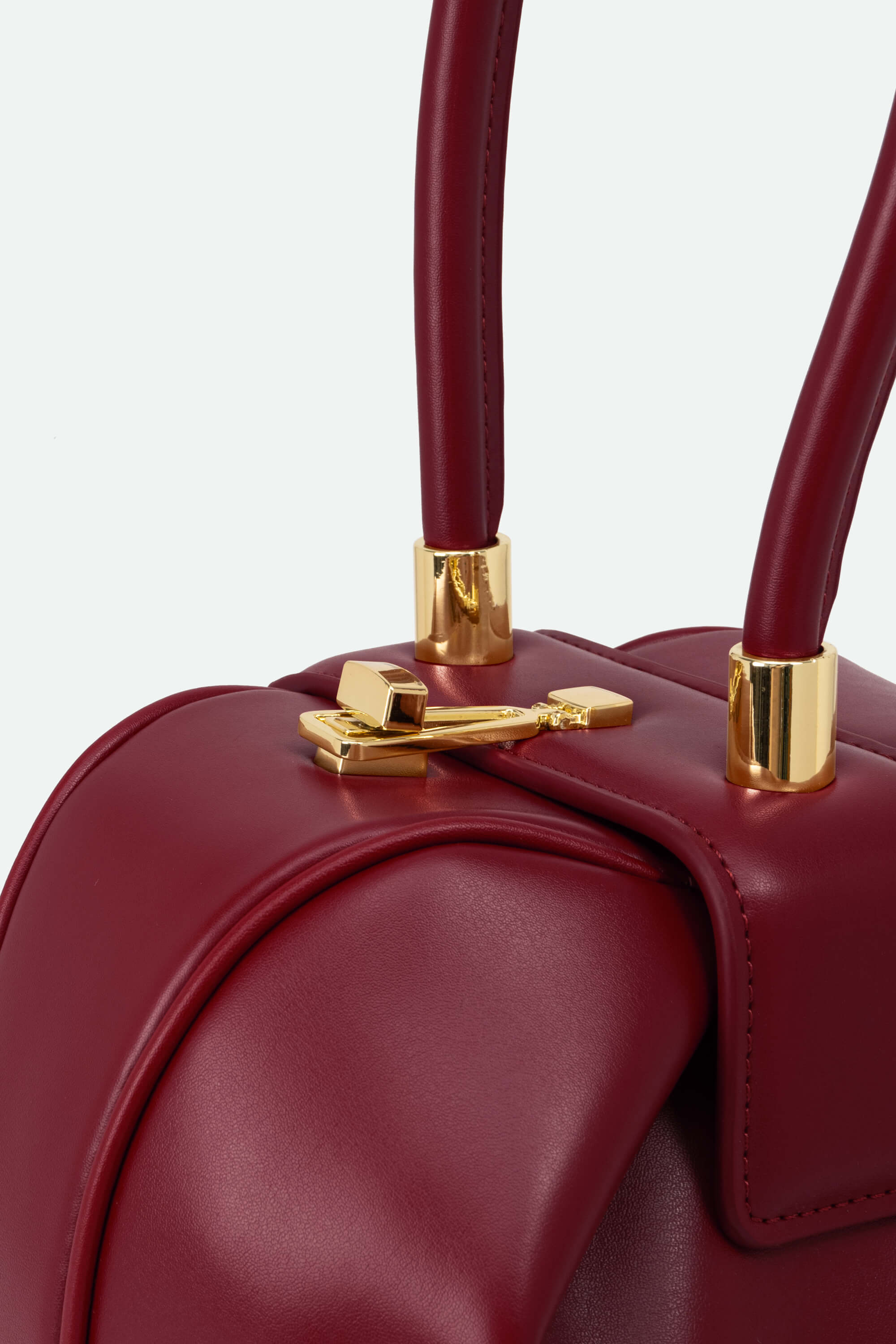 Close-up of a red handbag with gold accents on a white background