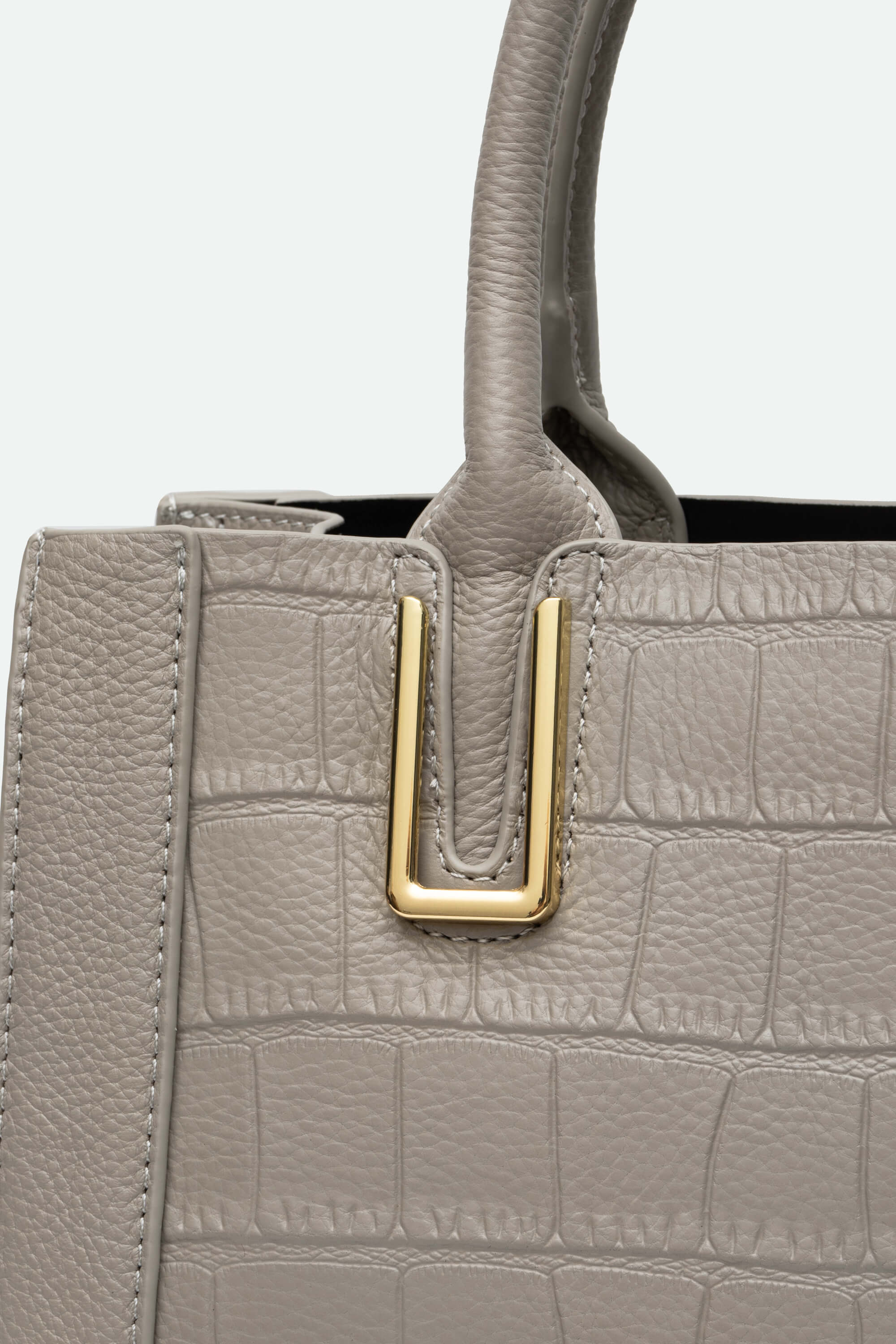 Close-up of a gray textured handbag with a gold buckle on a light gray background