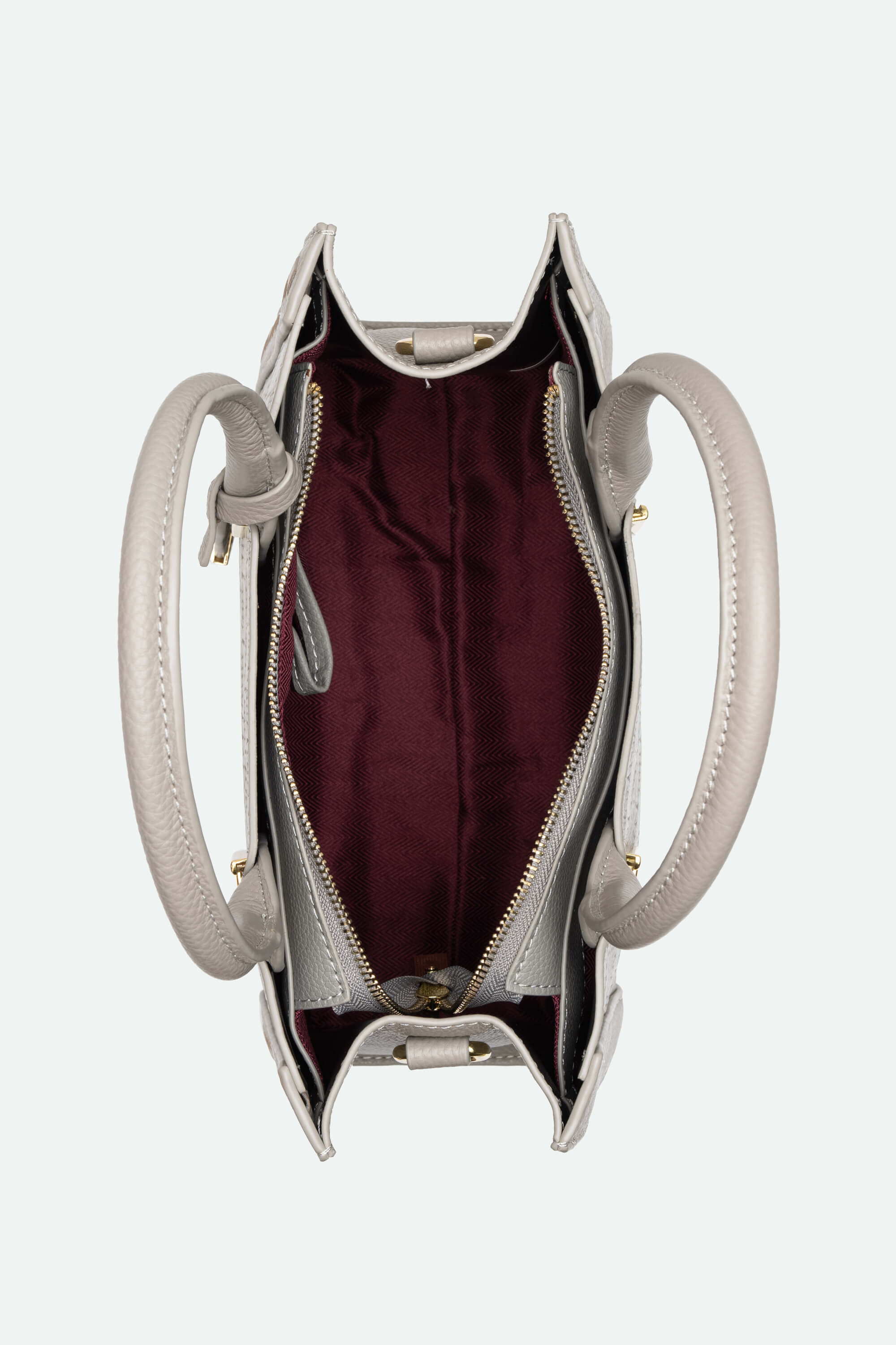 Unzipped handbag with burgundy interior on a white background