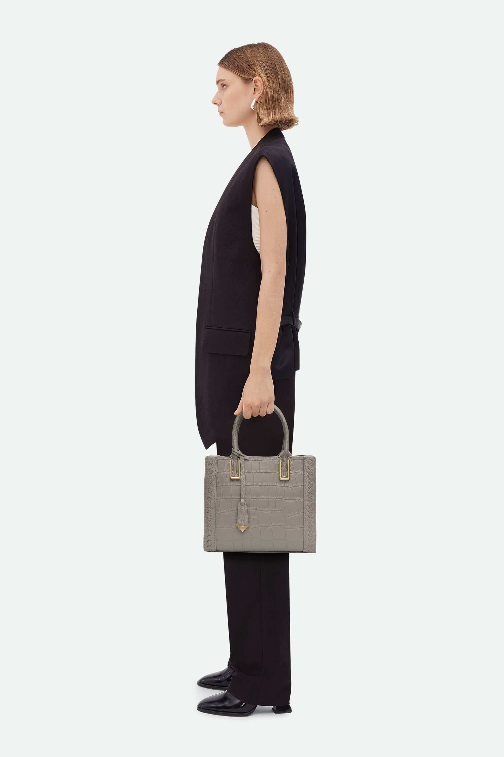Woman holding a gray handbag against a white background