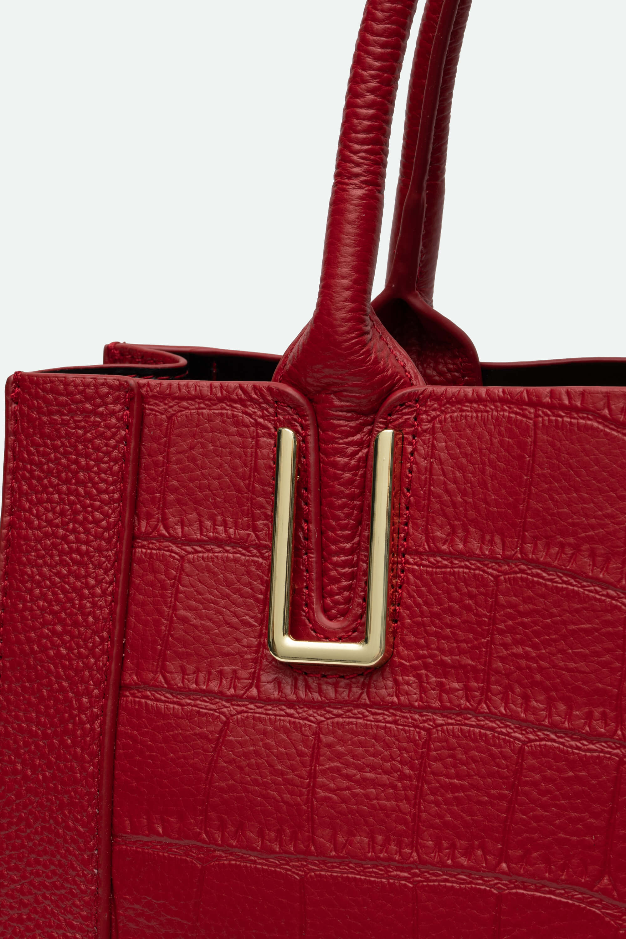 Red textured handbag with a gold buckle on a light gray background