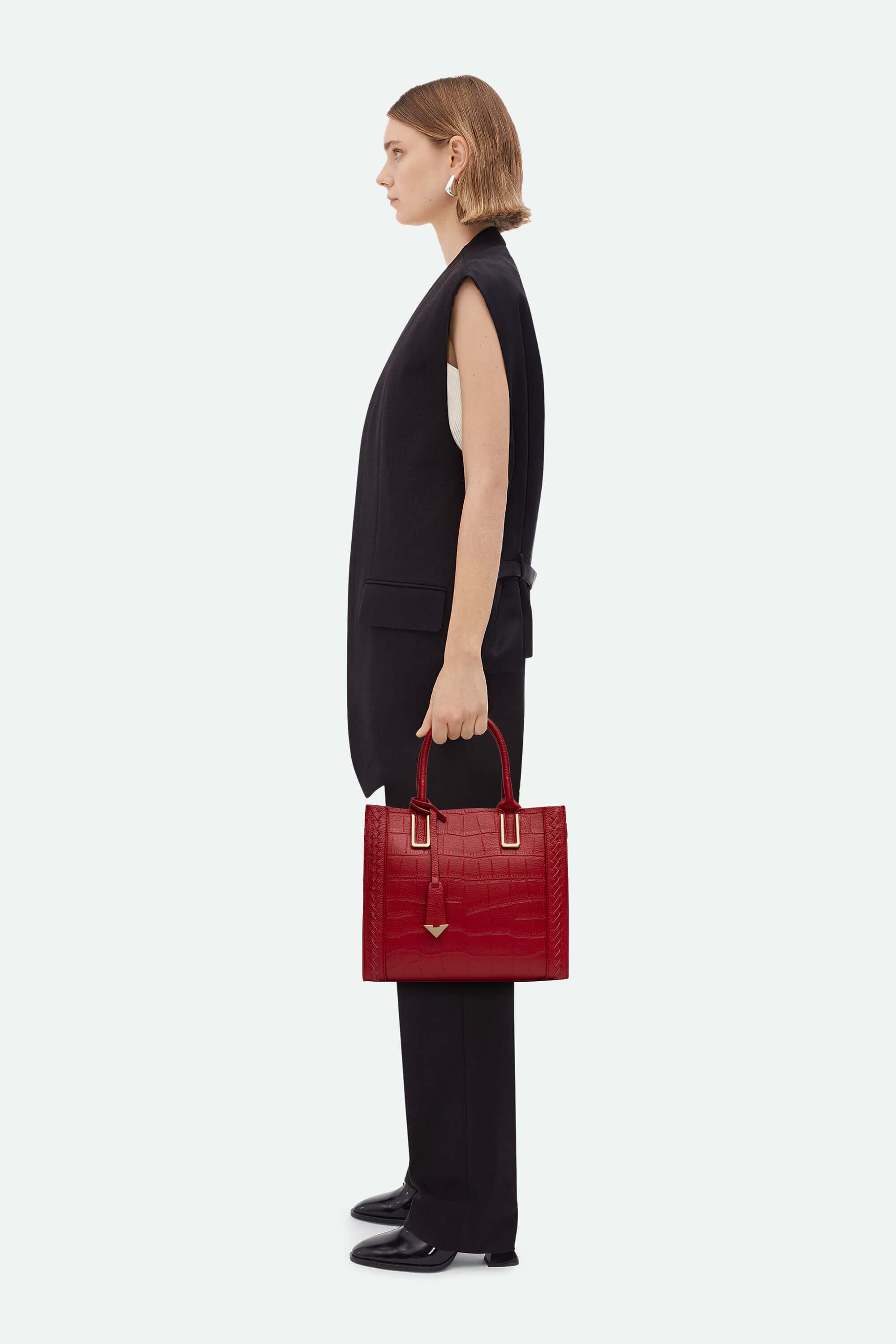Woman holding a red handbag against a white background