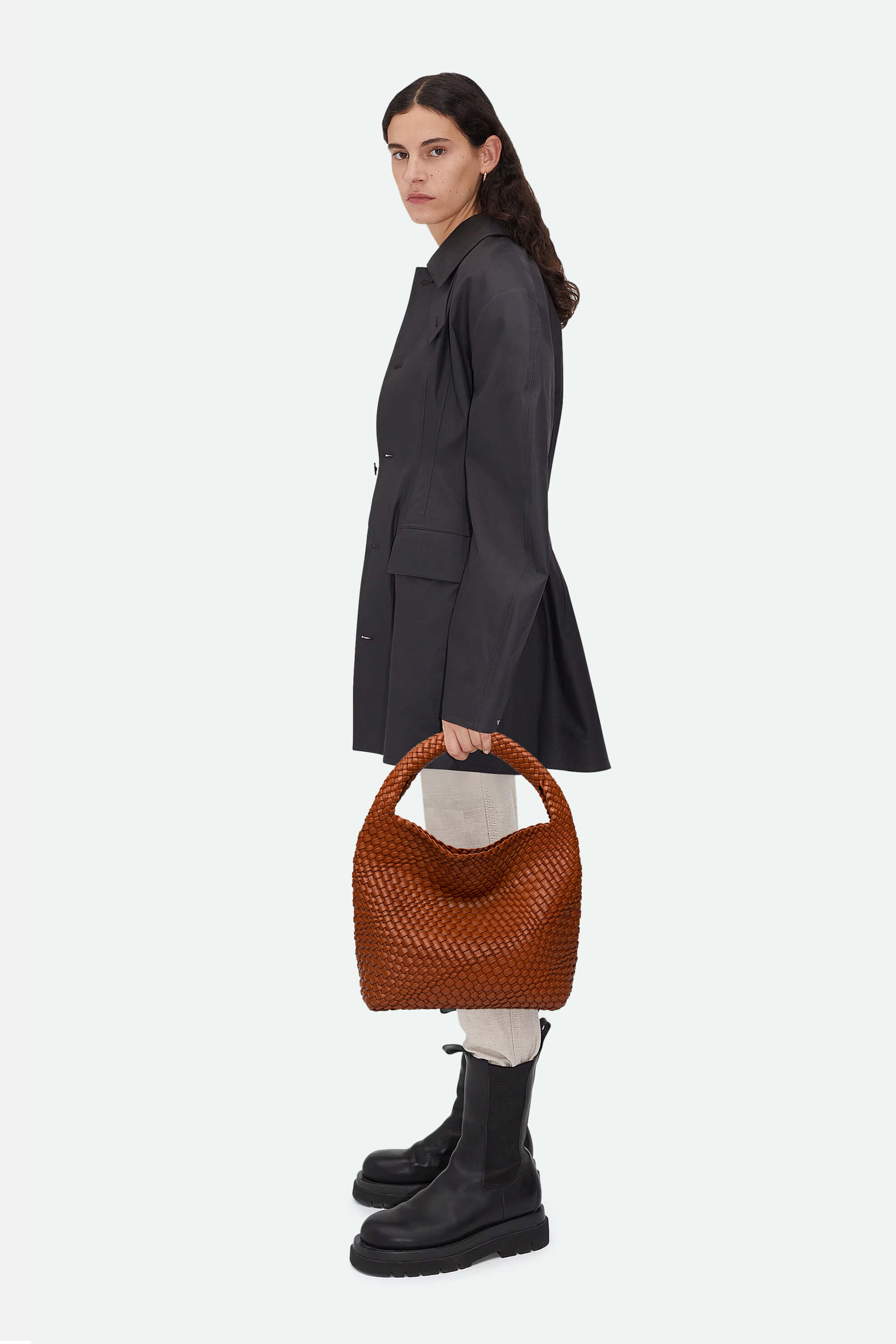 Woman holding a brown woven handbag against a white background