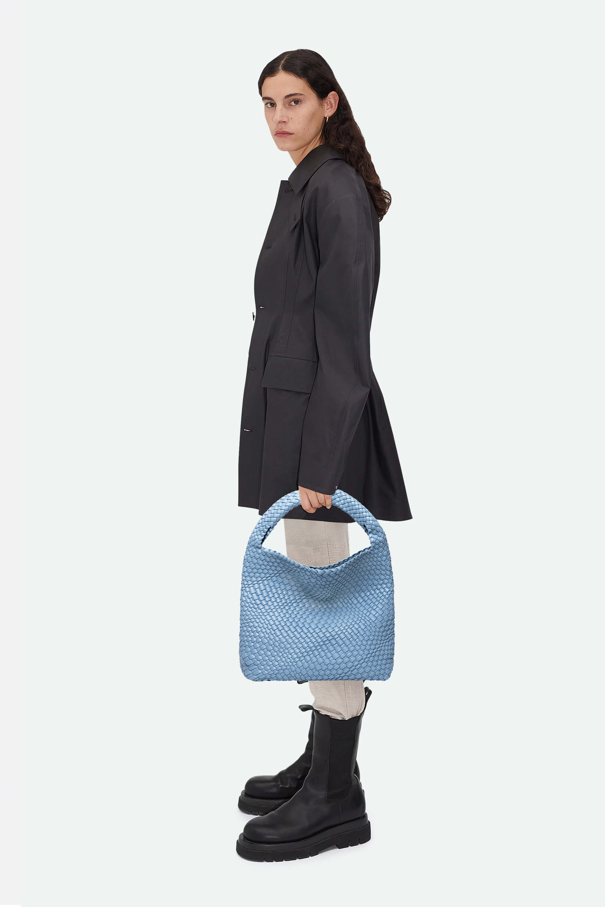 Woman holding a blue textured handbag against a white background