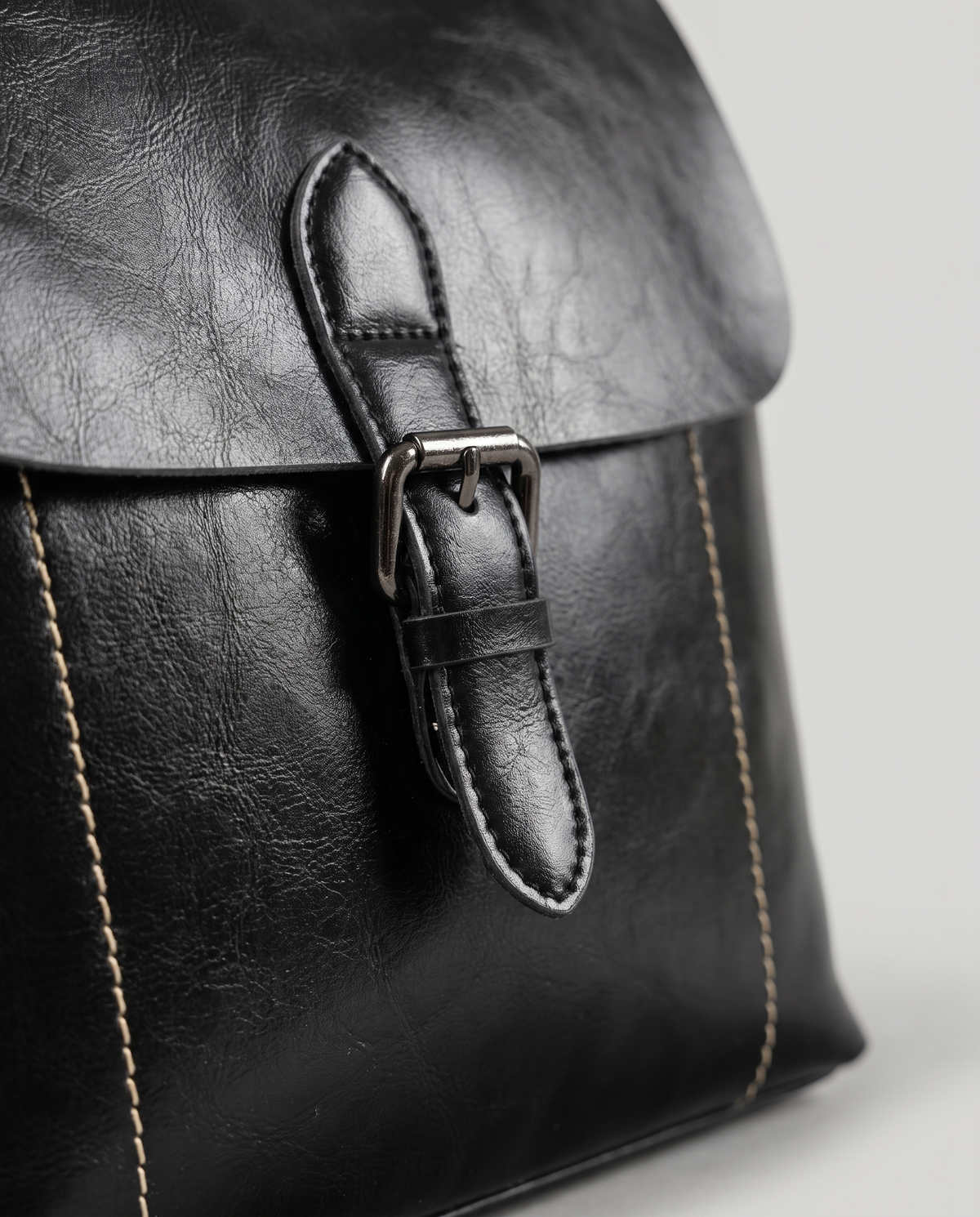 Ambler waxed leather backpack in Black – close-up of the buckle and contrast stitching