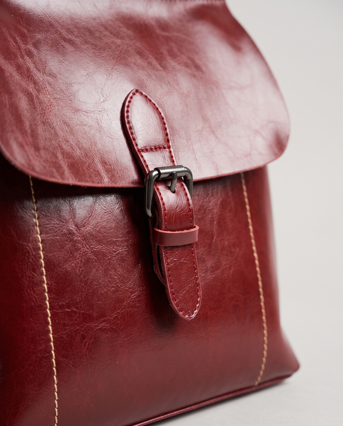 Ambler waxed leather backpack in Red – close-up of the buckle and contrast stitching