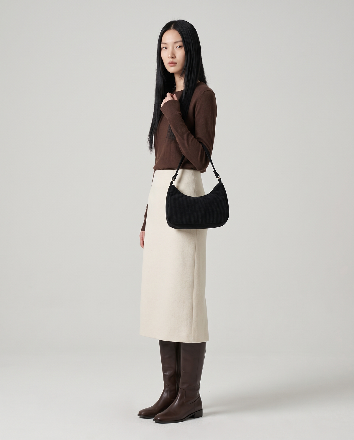 Aura corduroy shoulder bag in Black – model wearing it on her shoulder, full length