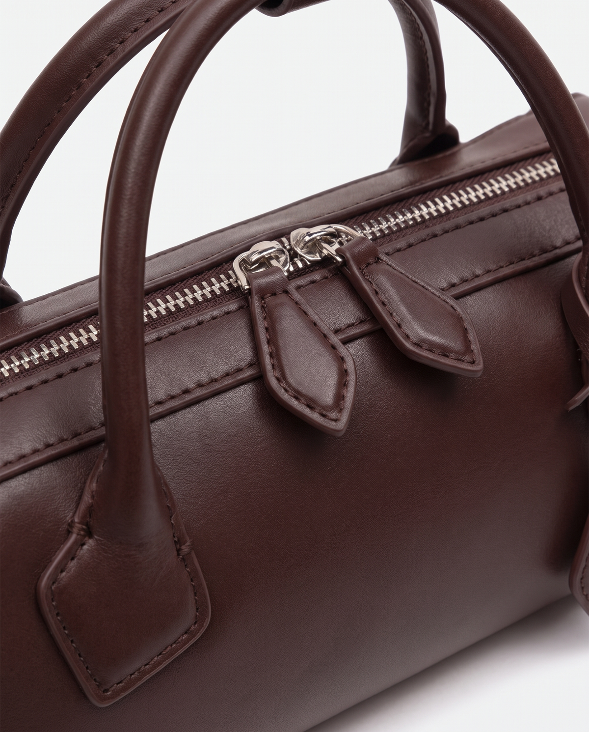 Curve leather barrel bag in Brown – close-up of the handle and zip pulls