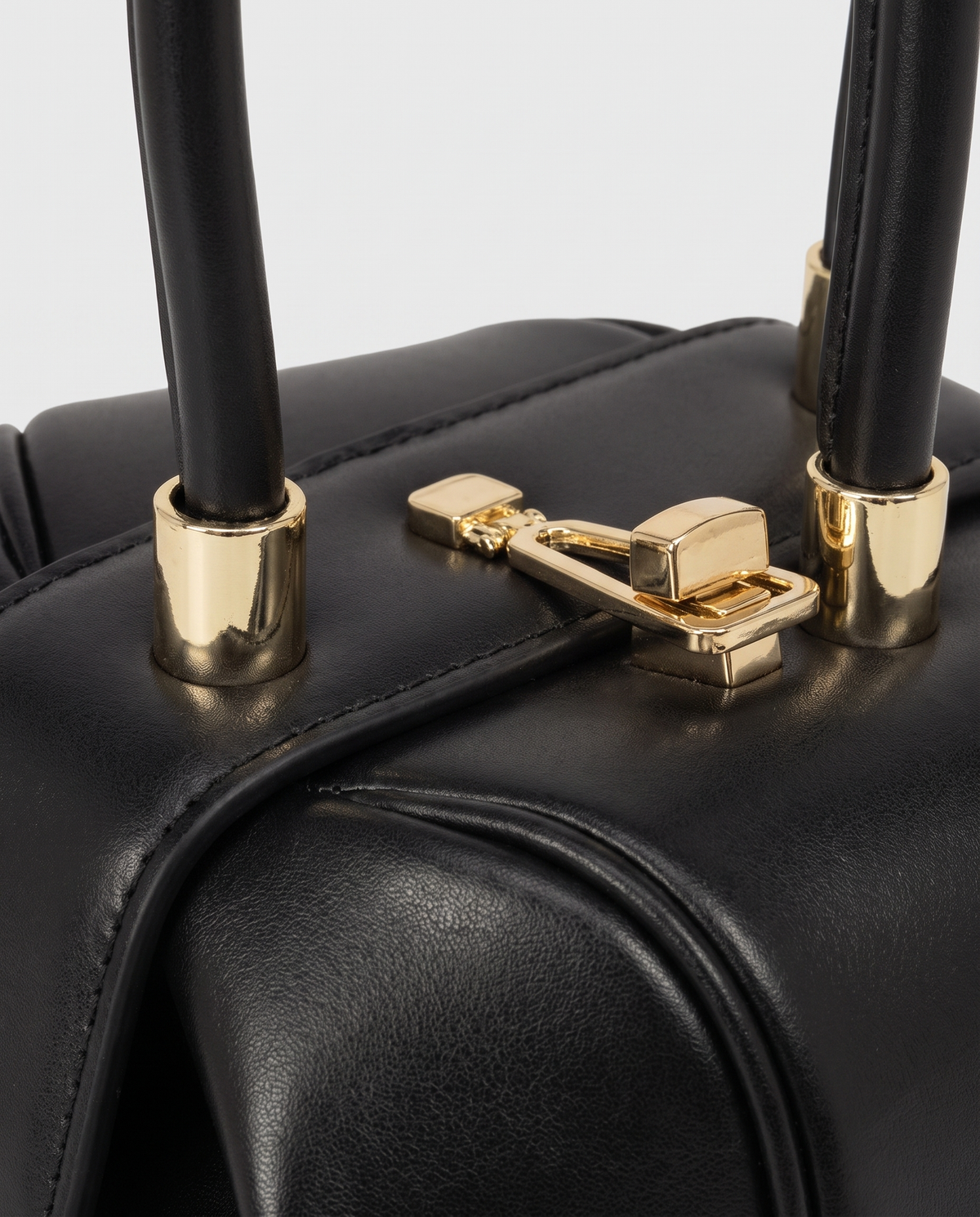 Dumpling Maxi leather top-handle bag in Black – close-up of the gold twist-lock and handle fittings