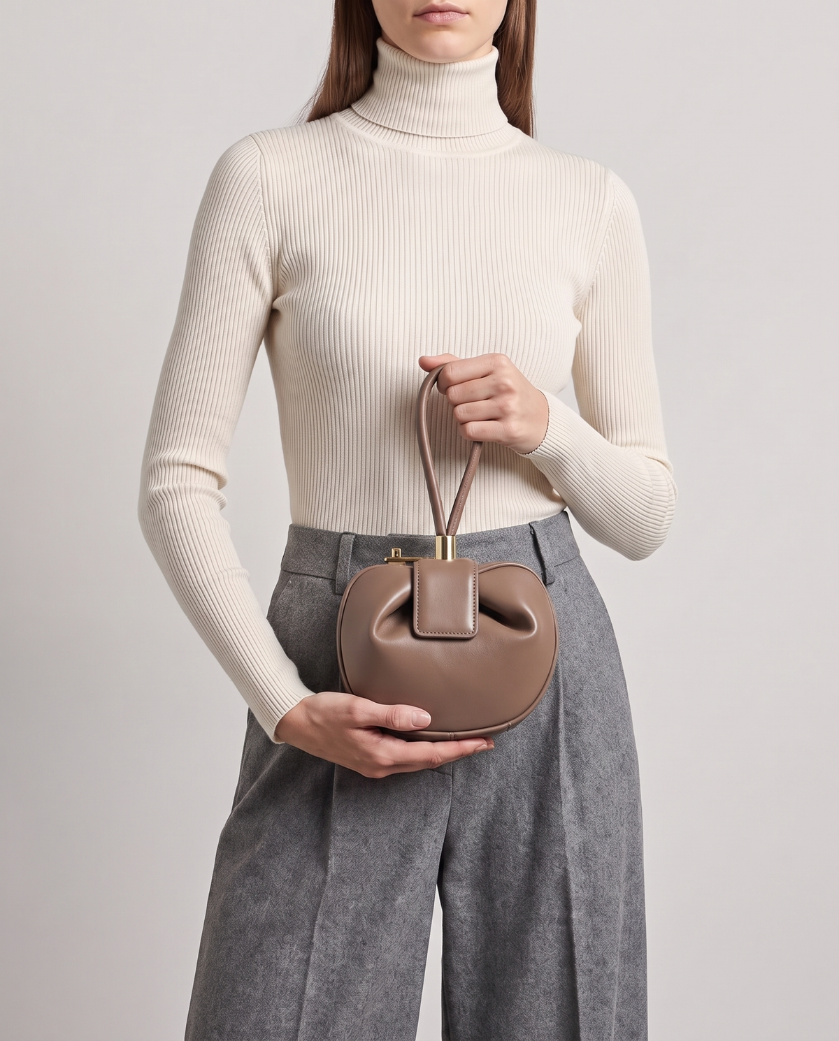 Dumpling Mini leather top-handle bag in Nude – model holding it at the waist