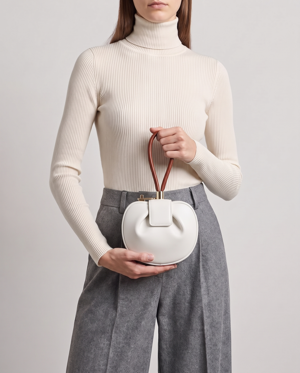 Dumpling Mini leather top-handle bag in White – model holding it at the waist