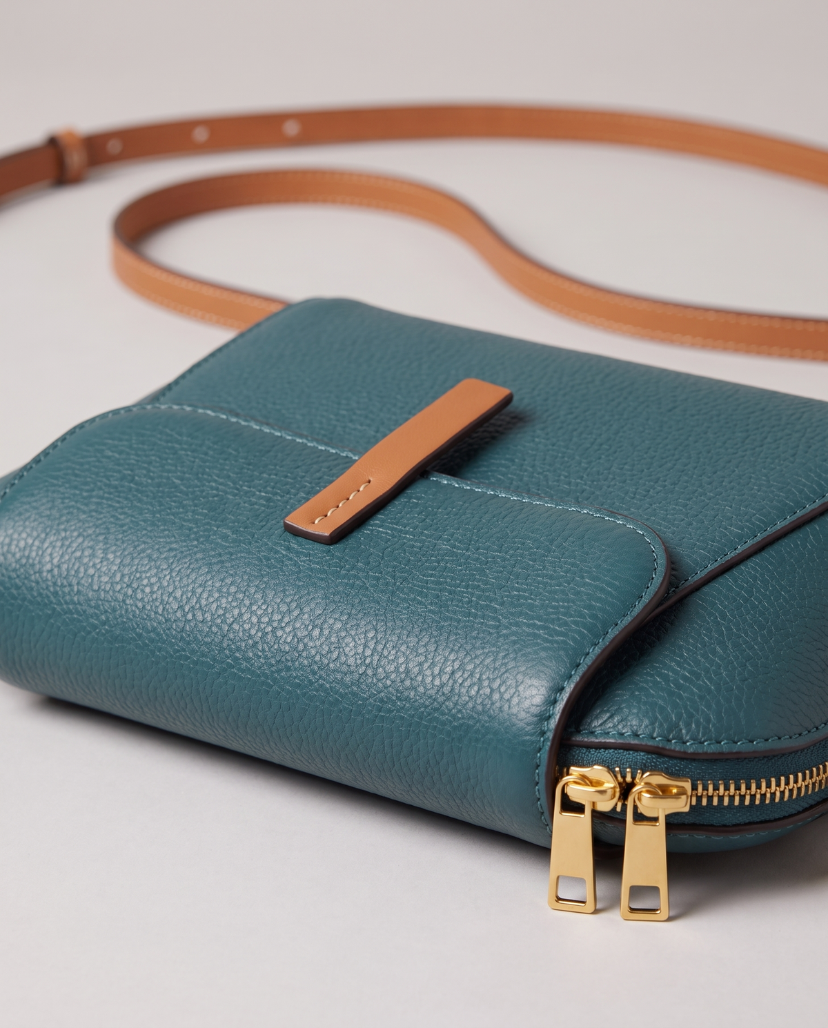 Elara mini leather crossbody in Teal – close-up of the tan tab, zips and pebbled leather