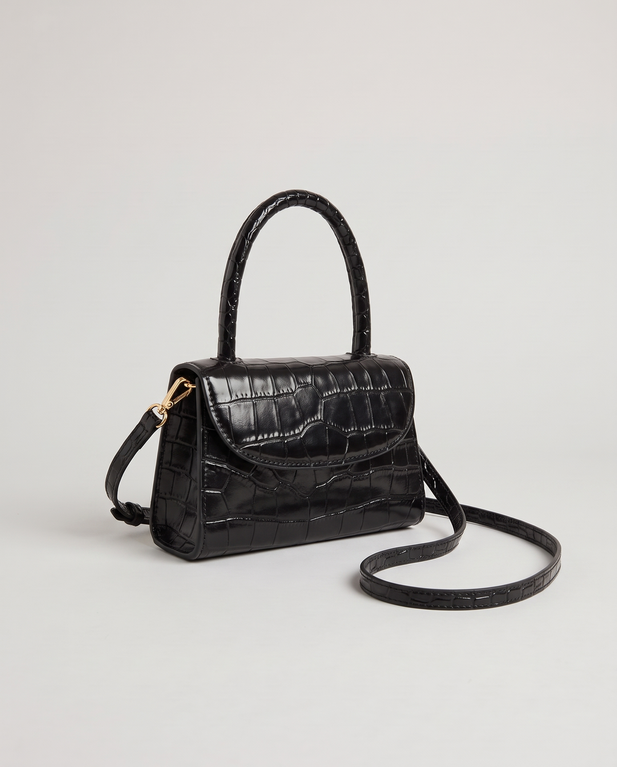Fern mini croc top-handle bag in Black – three-quarter view with the crossbody strap