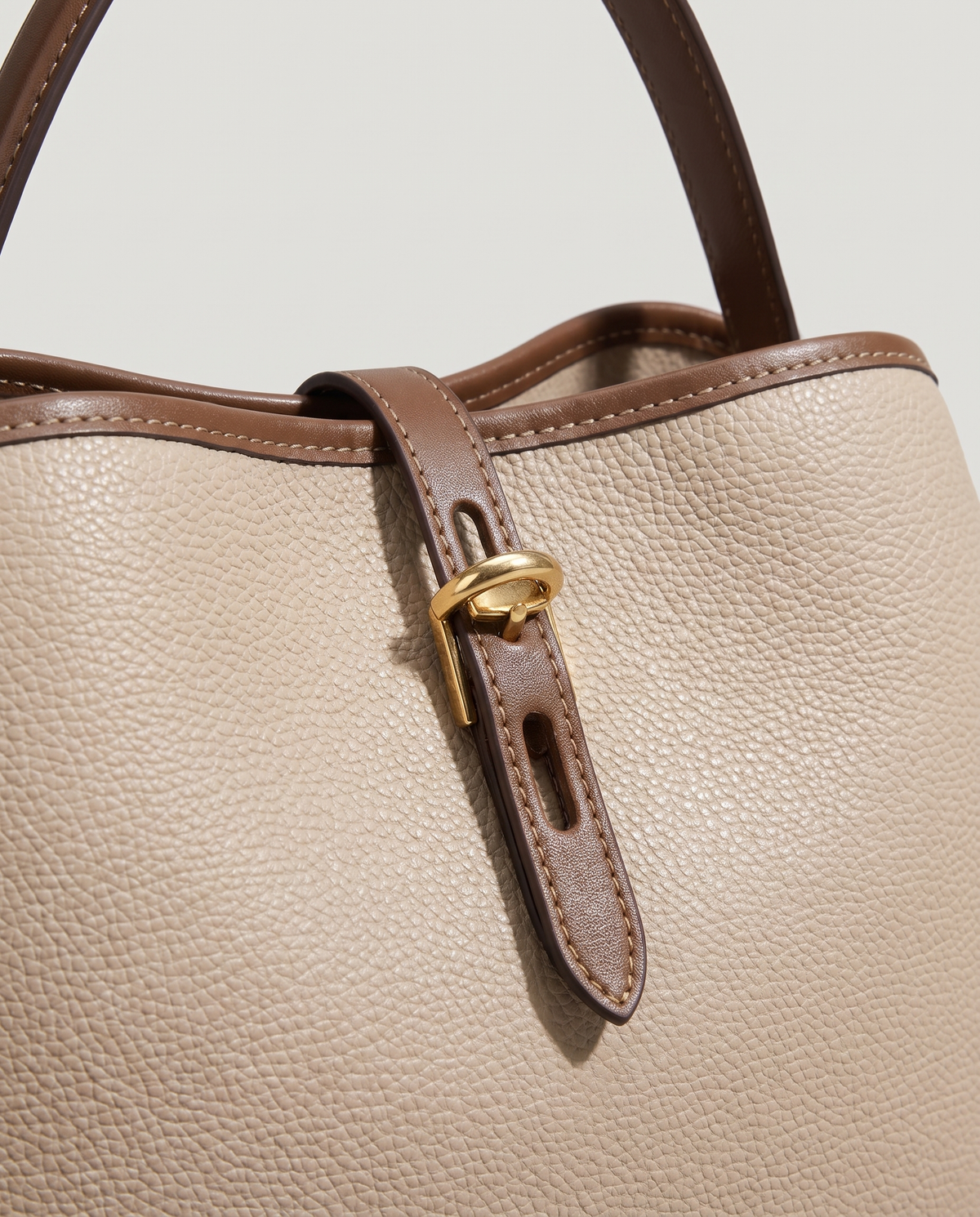 Fiora carryall bag in Beige – close-up of the belt tab and gold buckle