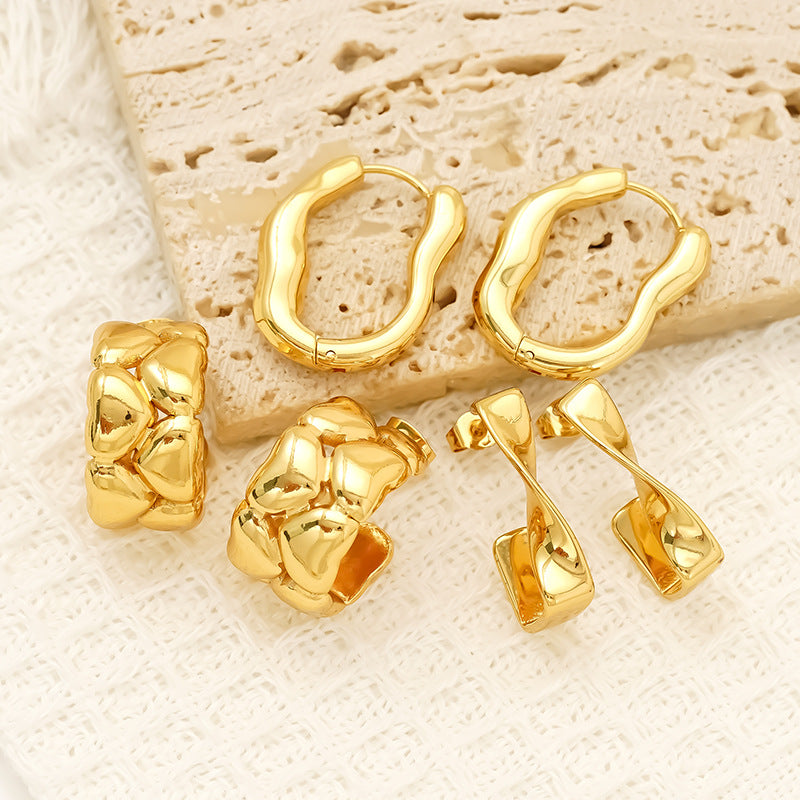 Collection of golden irregular hoop earrings on beige textured fabric