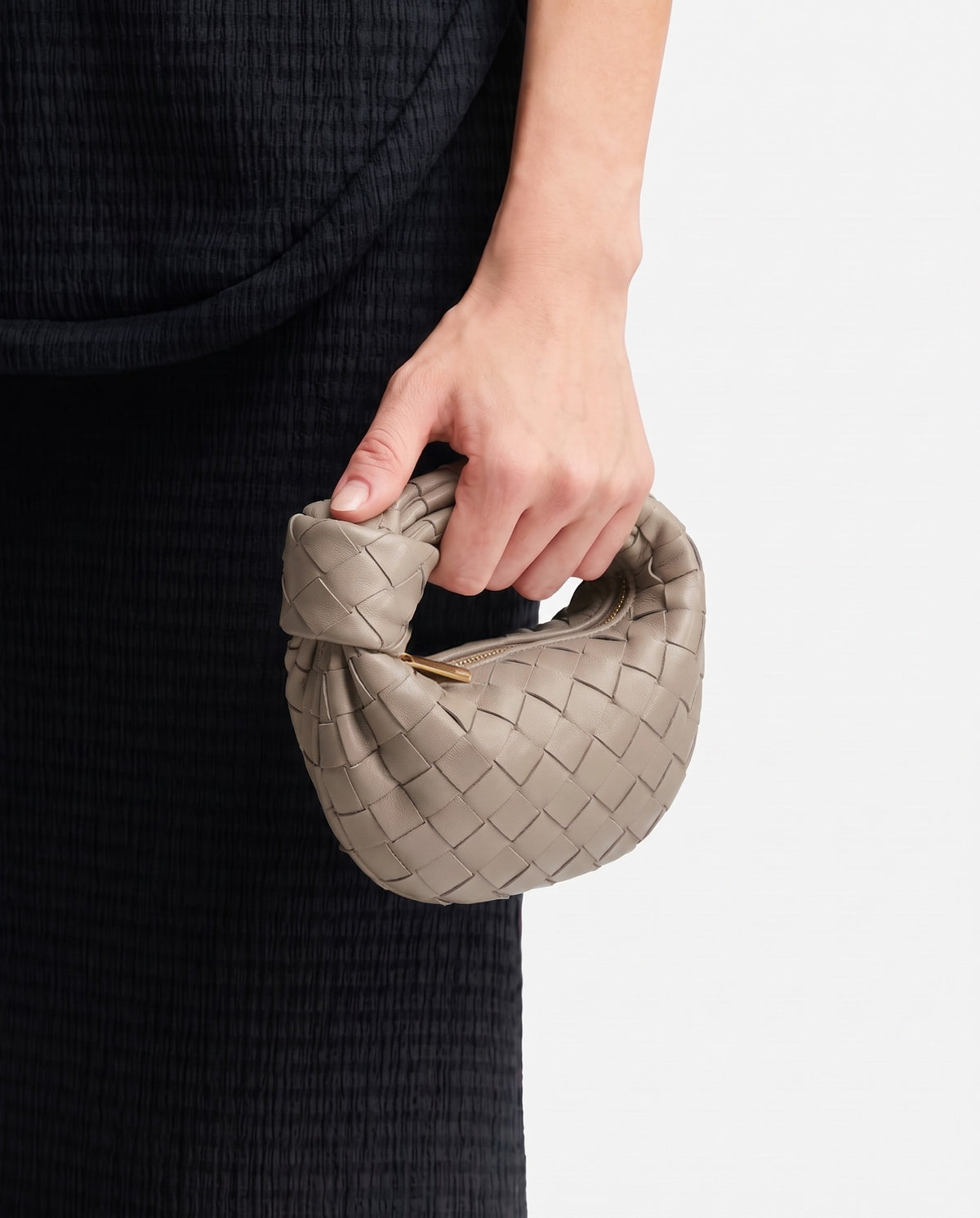 Knot Mini woven leather bag in Camel – held in the hand, showing true size