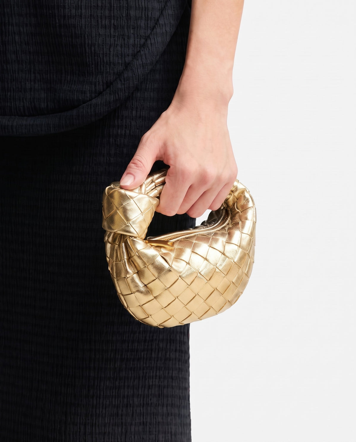 Knot Mini woven leather bag in Gold – held in the hand, showing true size