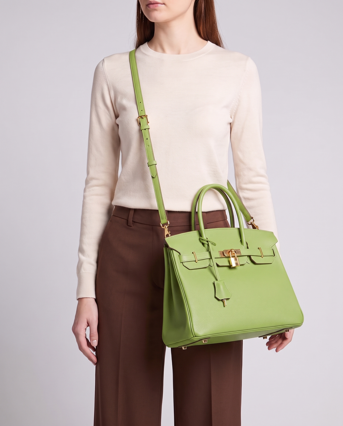 Lock Medium leather top-handle bag in Avocado – model wearing it crossbody on the detachable shoulder strap