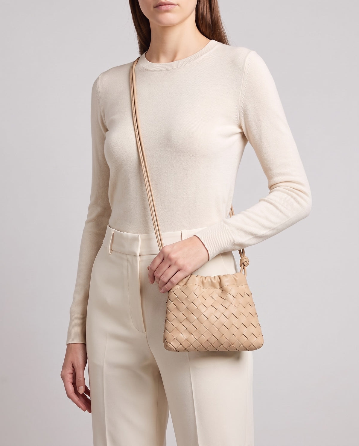 Model wearing the Serata woven leather clutch in Beige crossbody