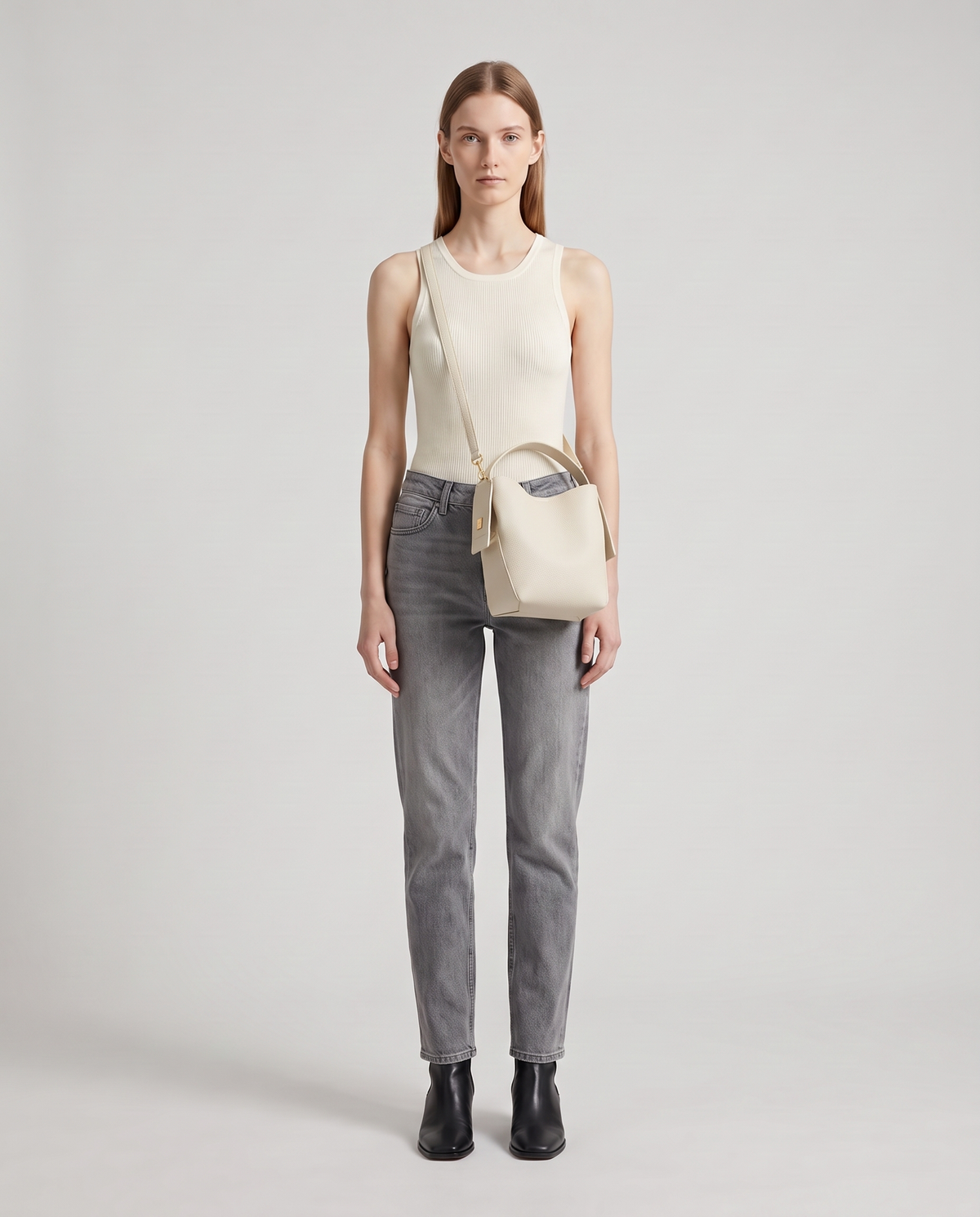 Transit leather bucket bag in Chalk – model wearing it crossbody, full length