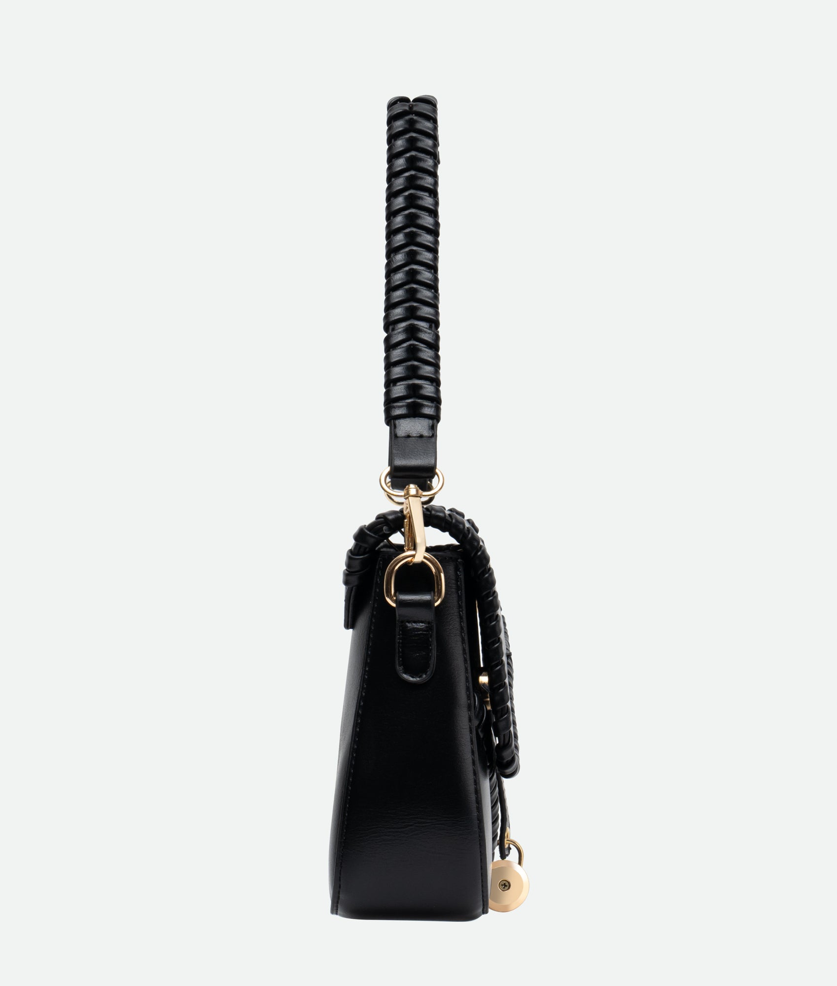 A black saddle bag with gold accents and a braided handle, crafted from vegan leather, featuring intricate stitching on a model
