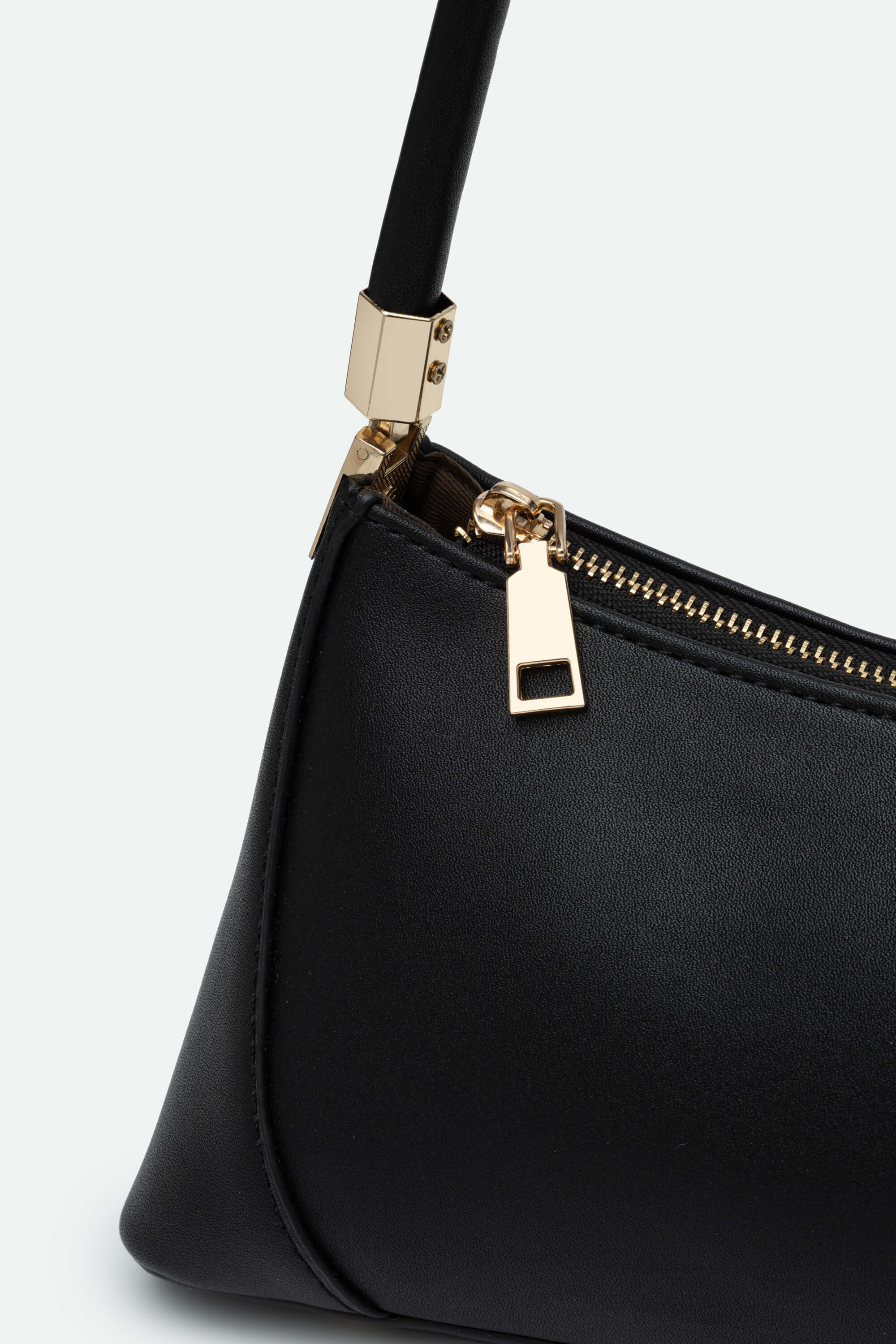 Black handbag with gold zipper on a light gray background