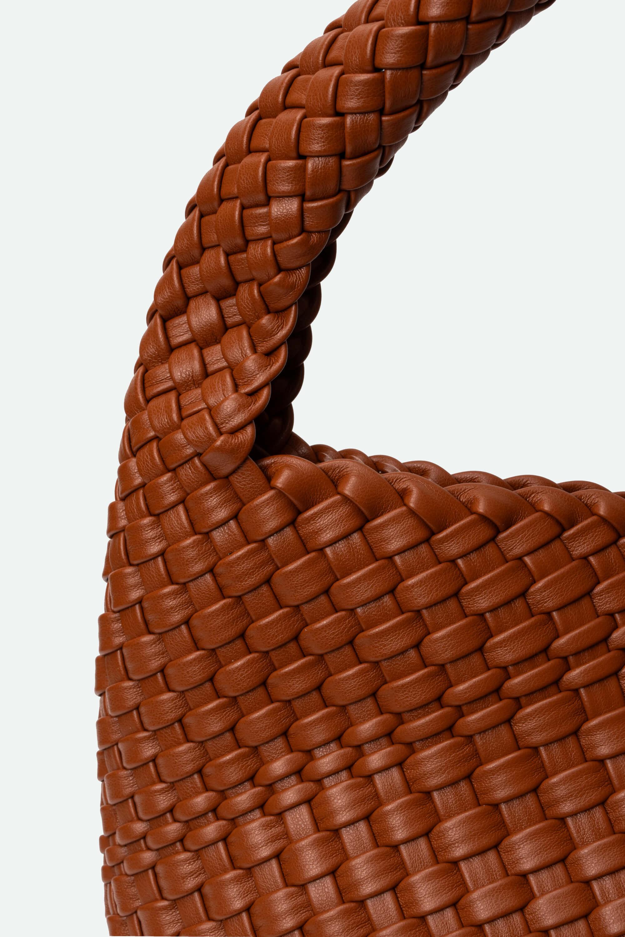 Close-up of a brown woven leather handbag handle on a white background