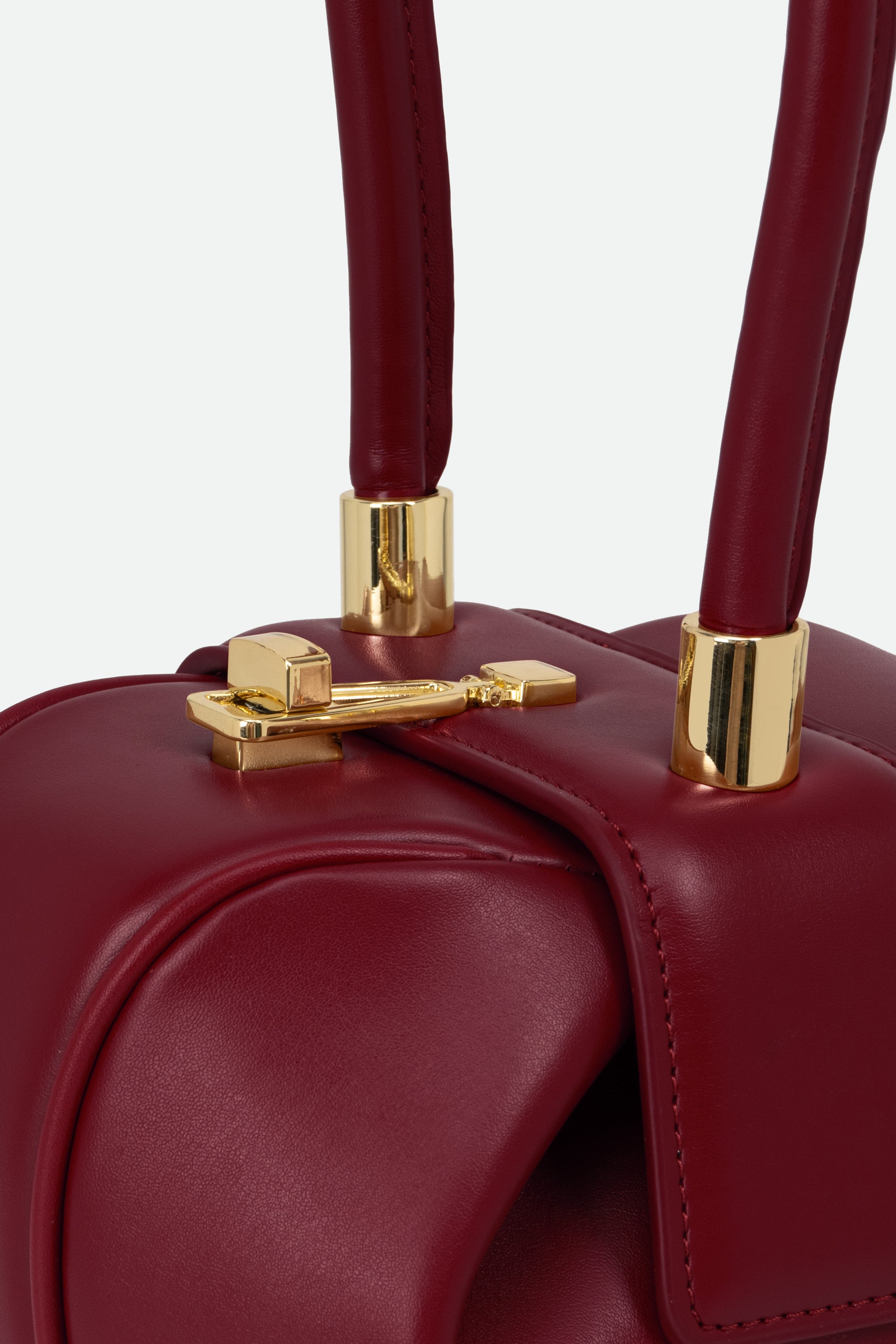 Close-up of a red handbag with gold hardware on a light gray background