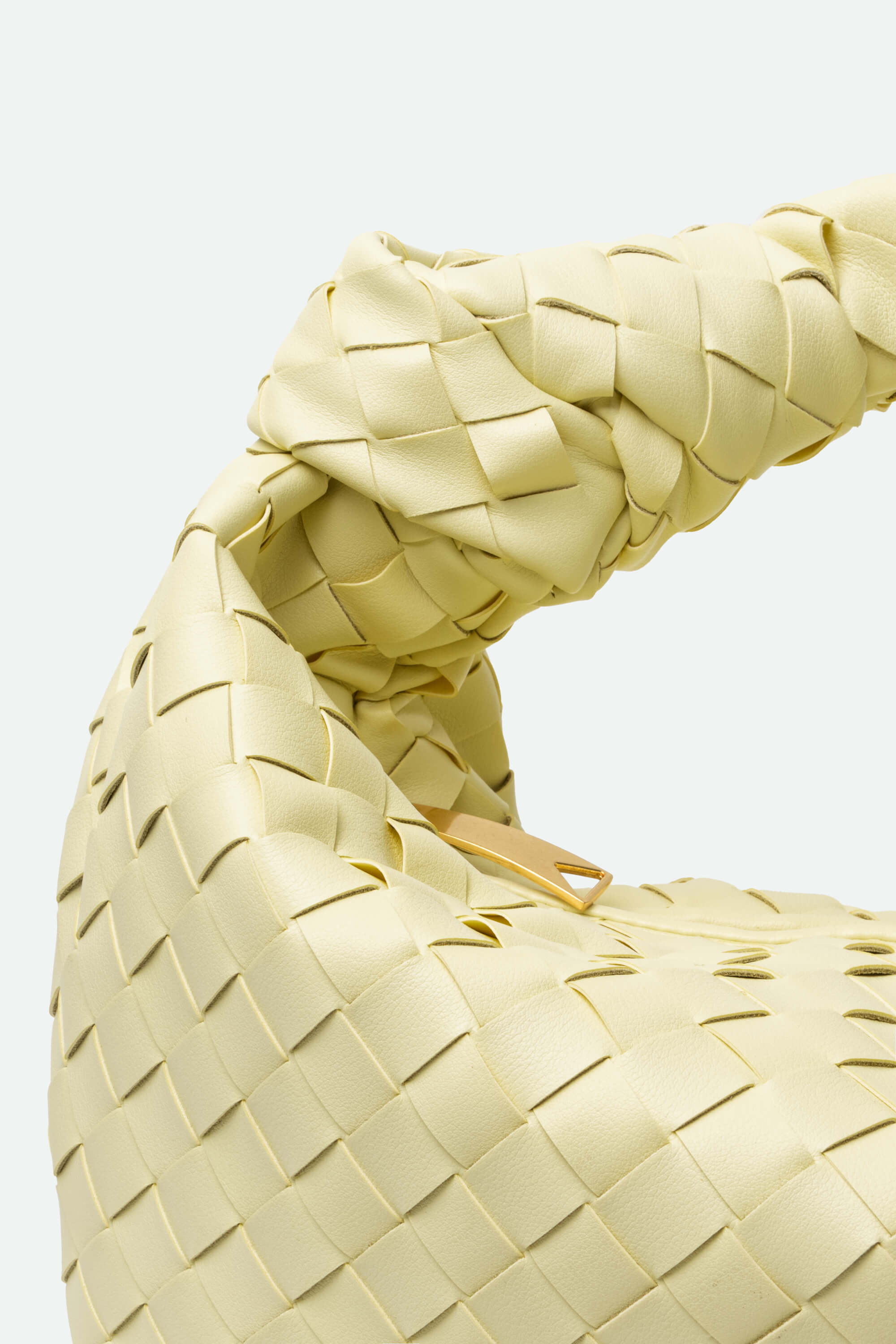 Close-up of a woven beige leather handbag on a light background