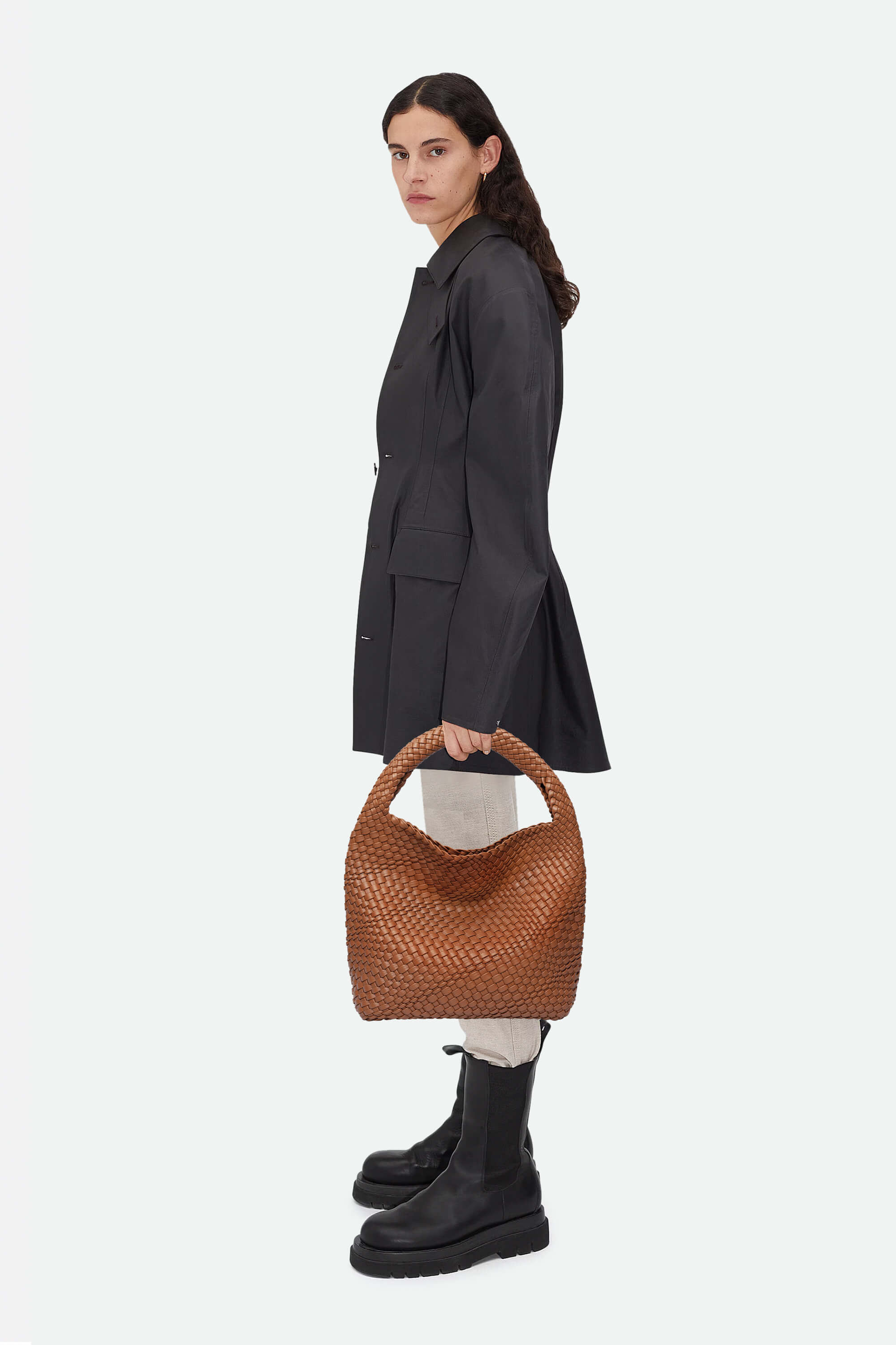 Woman holding a brown woven handbag against a white background