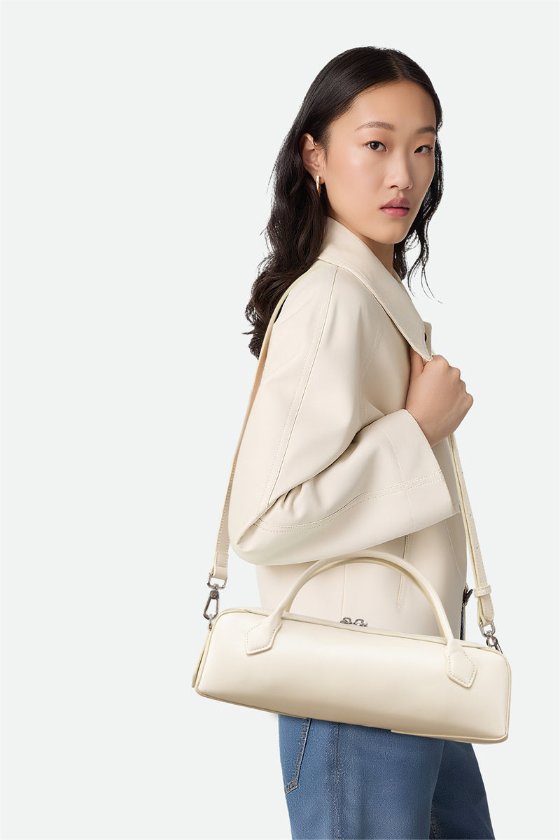 Woman holding a cream-colored handbag against a white background