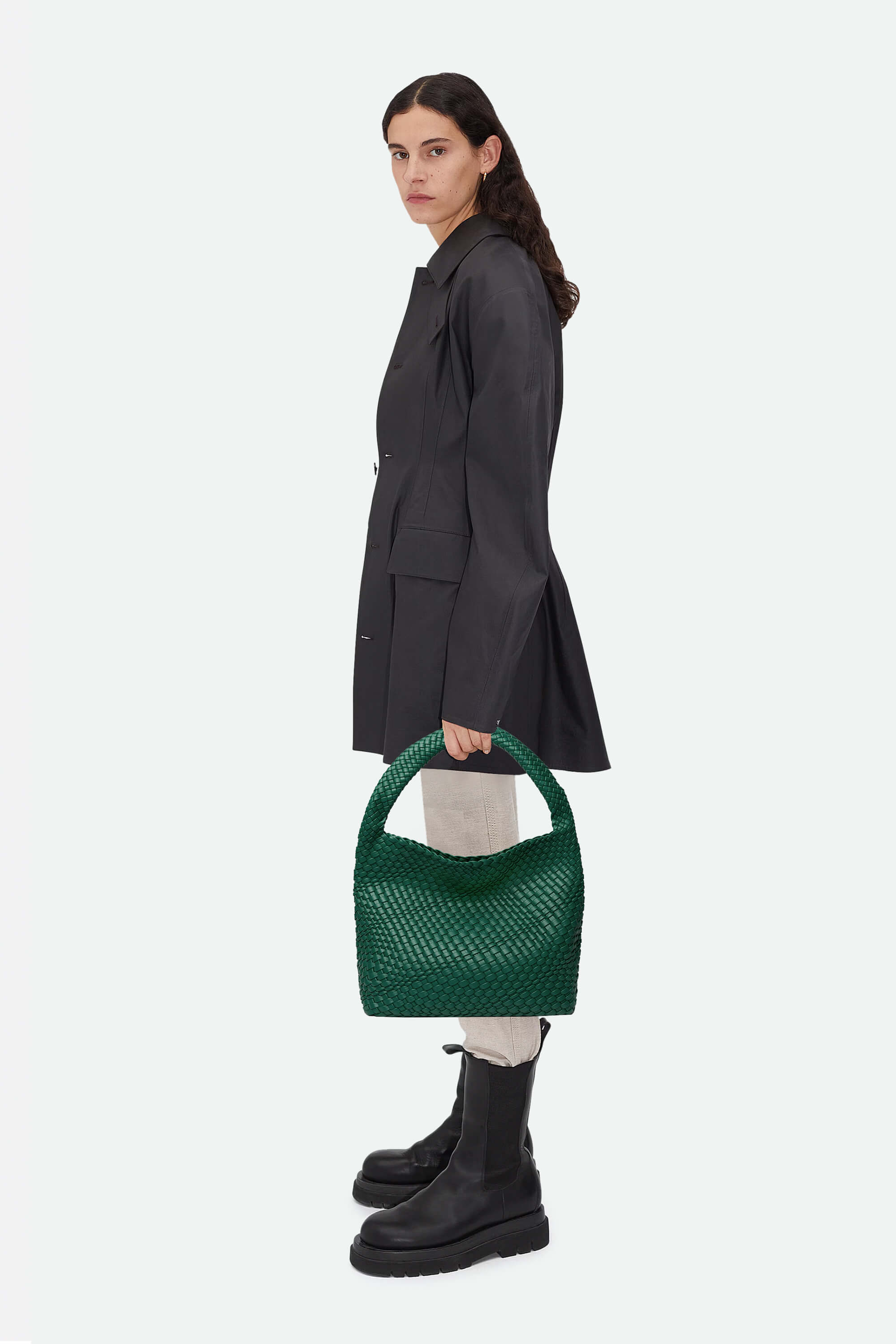 Woman holding a green handbag against a white background