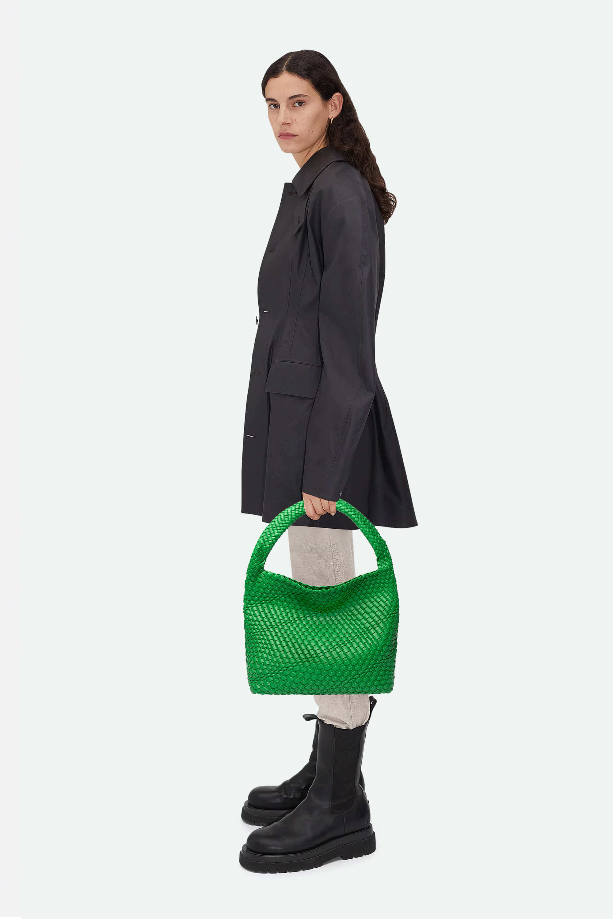Woman holding a green handbag against a white background