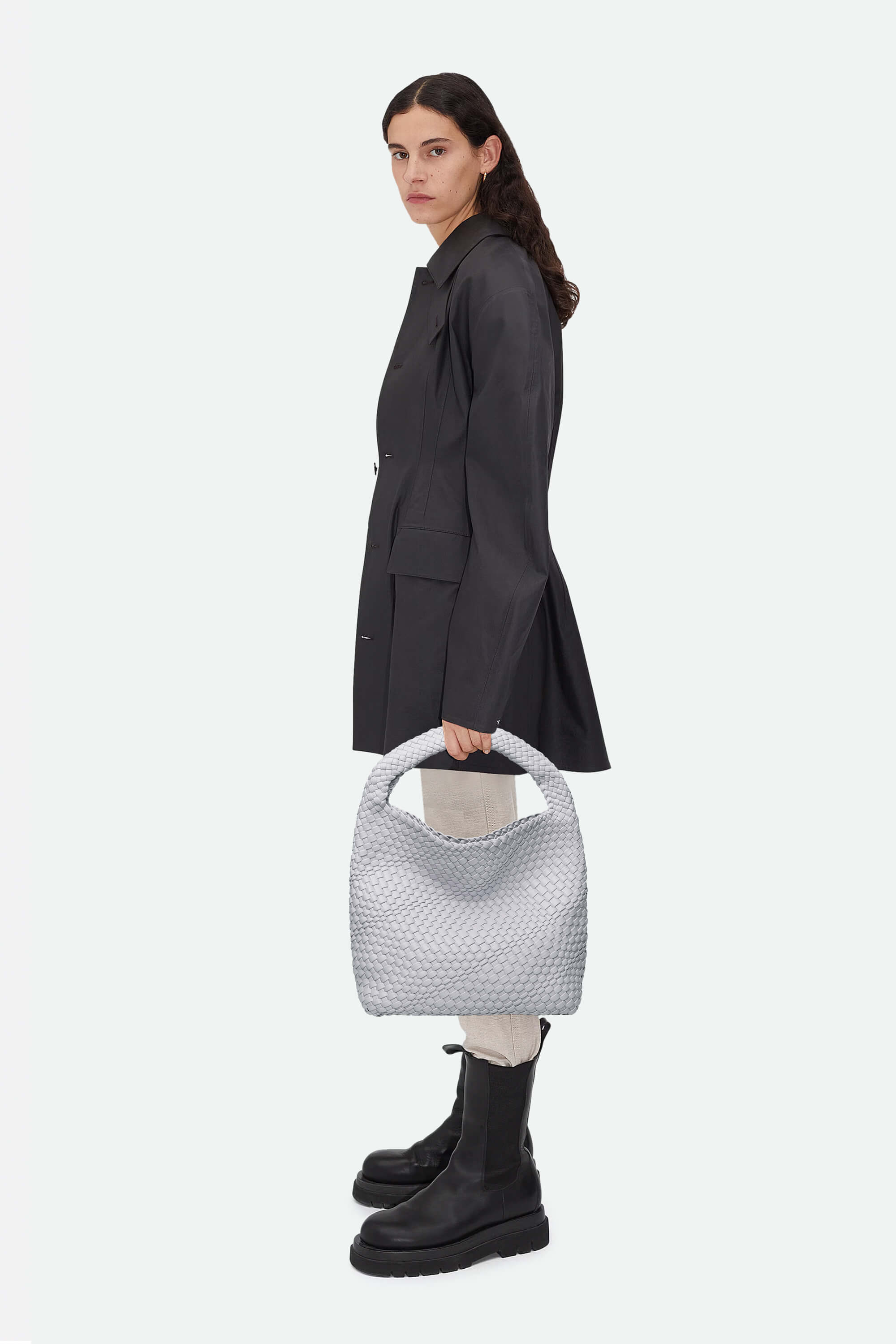 Woman holding a textured gray handbag against a white background