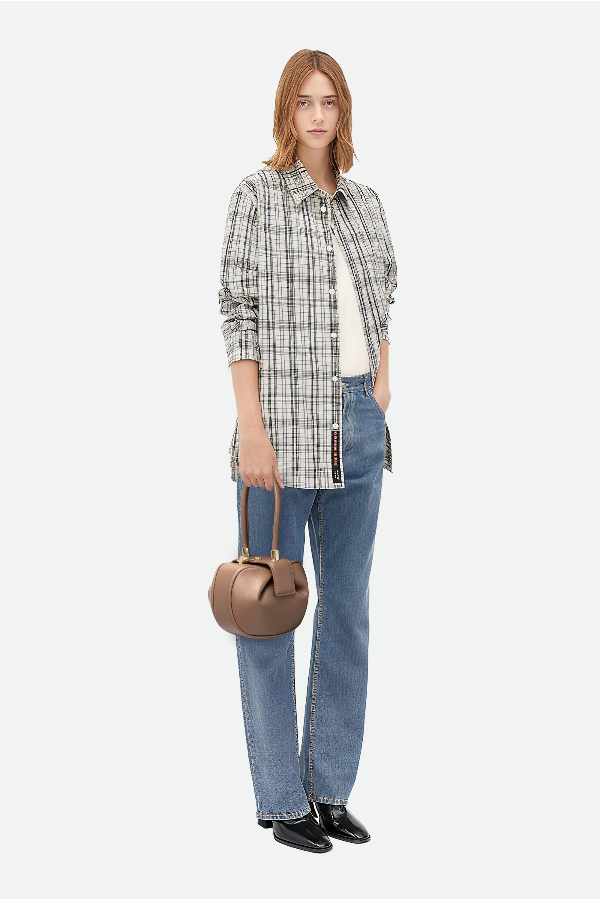 Woman wearing a plaid shirt, jeans, and holding a handbag on a white background