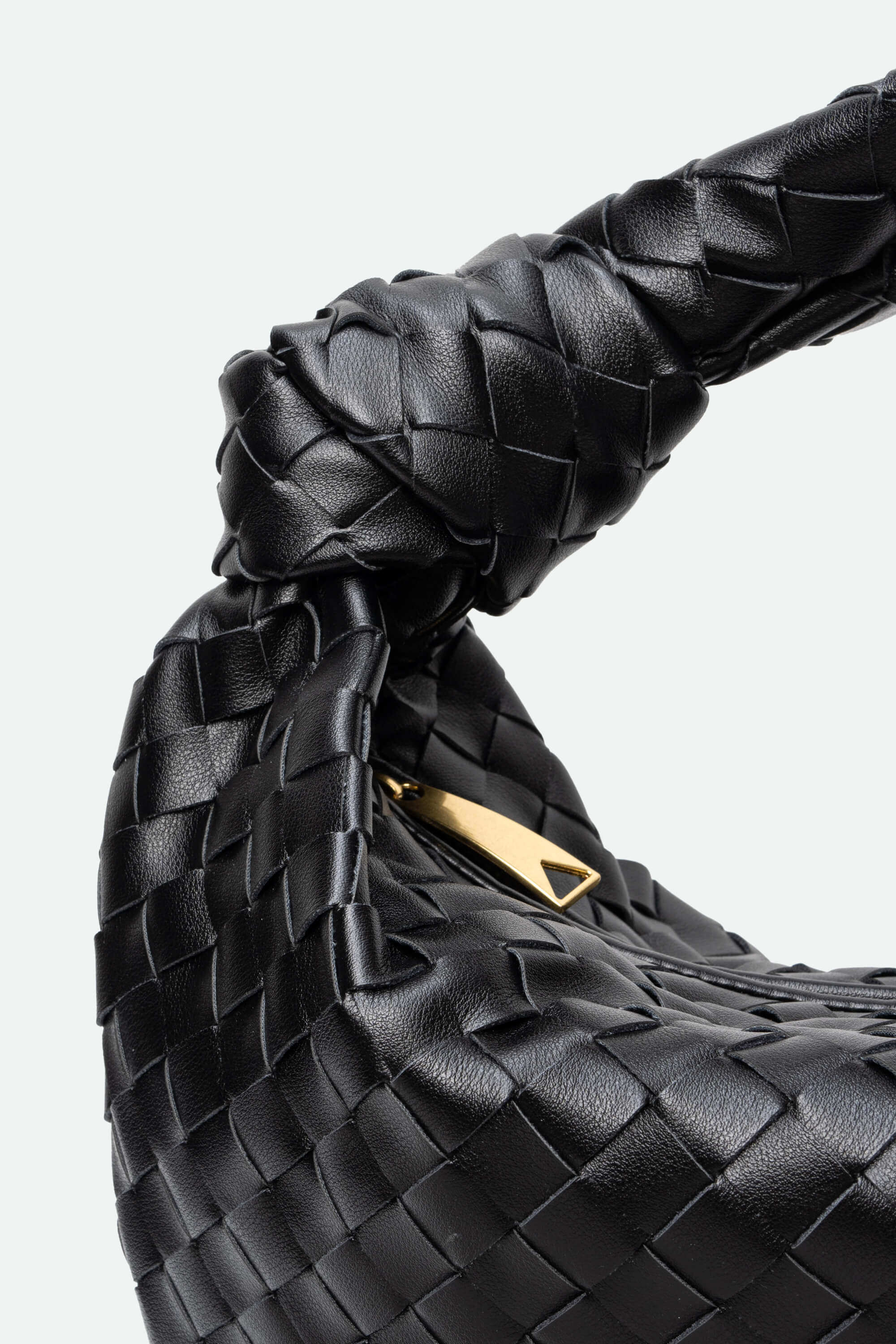 Black woven handbag with gold logo on a light gray background