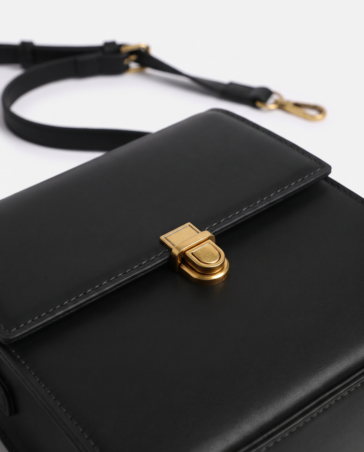 Bloc square vegan leather crossbody bag in Black – close-up of the gold push-lock clasp