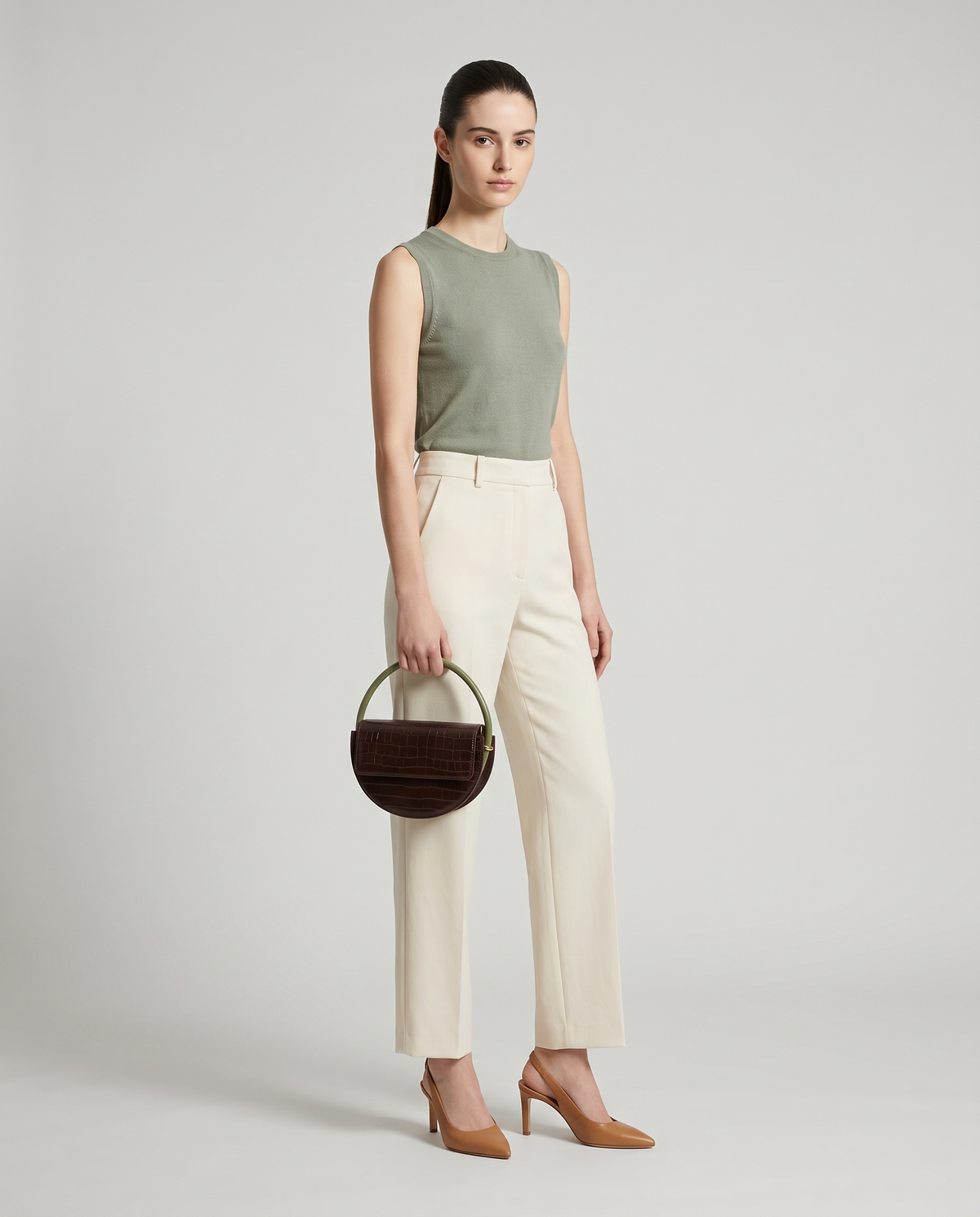 Crescent croc-embossed half-moon bag in Brown – model holding it by the round handle, full length