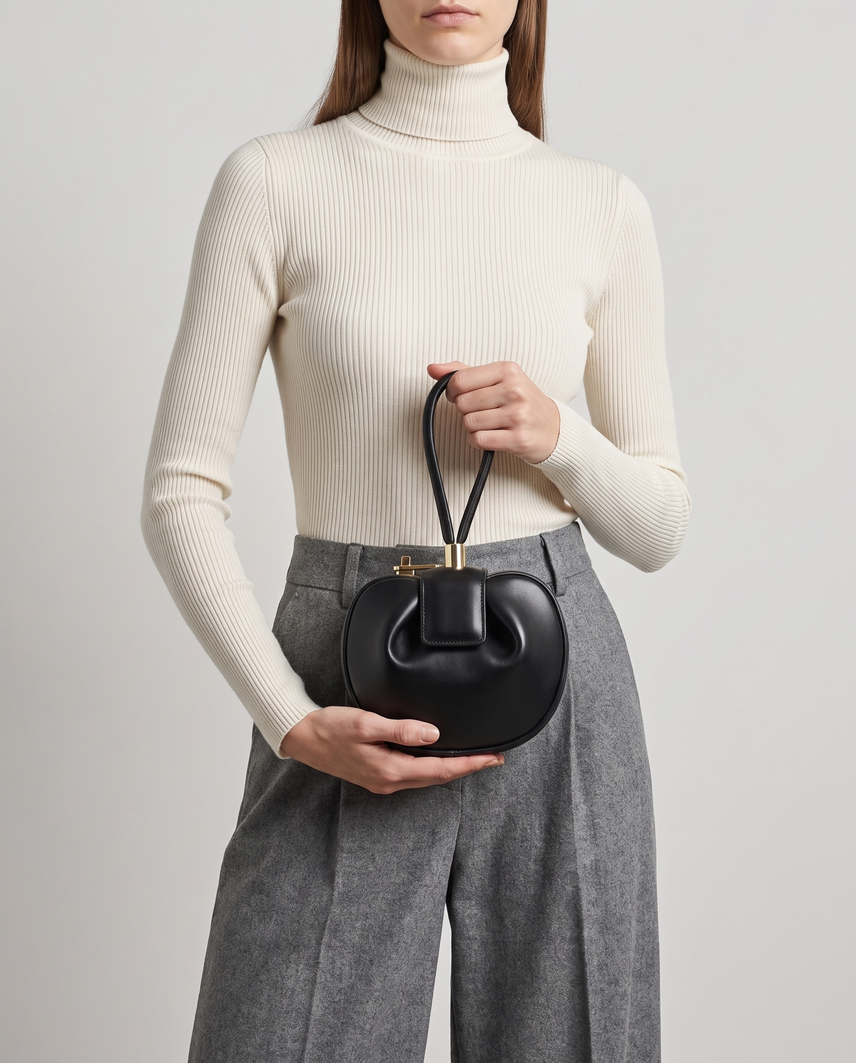 Dumpling Mini leather top-handle bag in Black – model holding it at the waist
