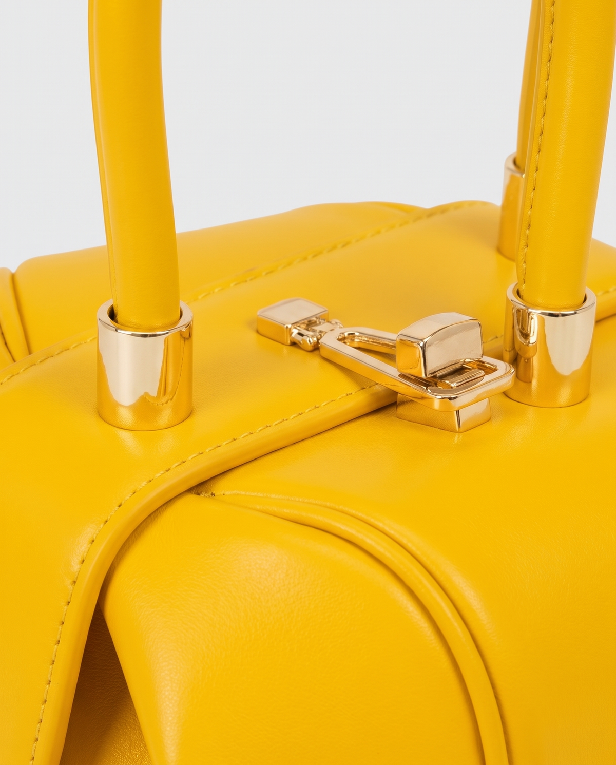 Dumpling Mini leather top-handle bag in Yellow – close-up of the gold twist-lock and handle fittings