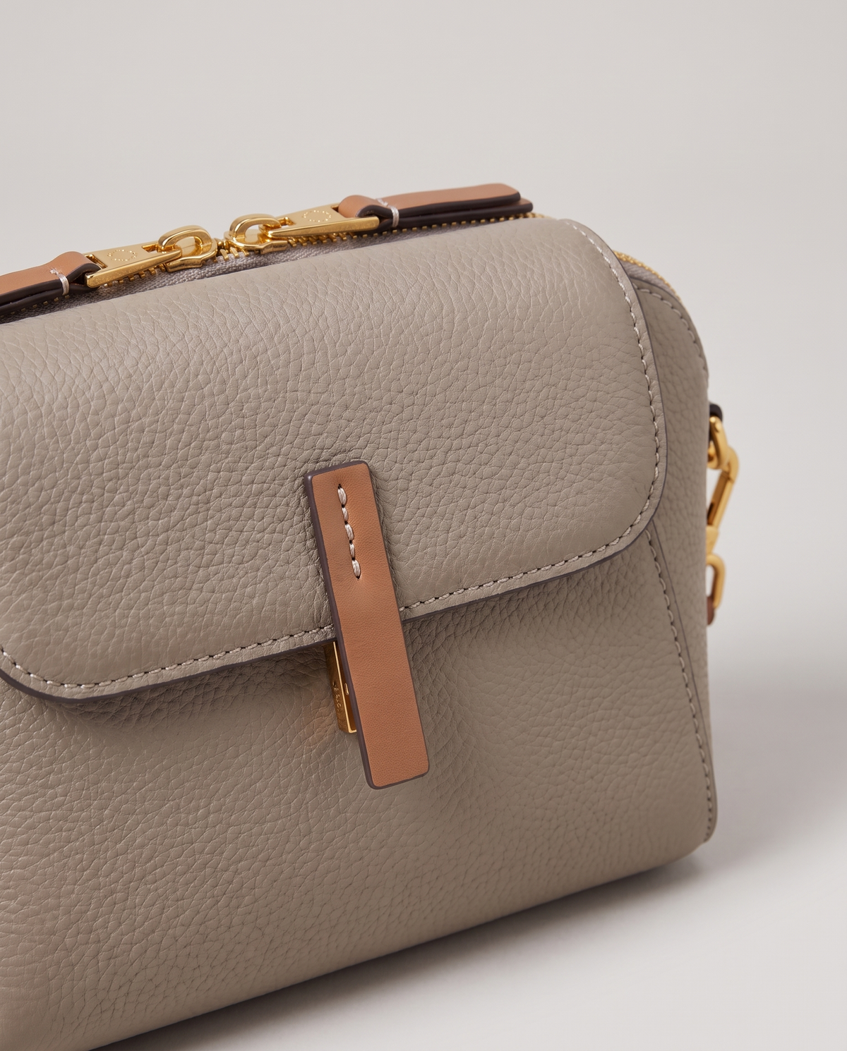 Elara mini leather crossbody in Grey – close-up of the tan tab and pebbled leather