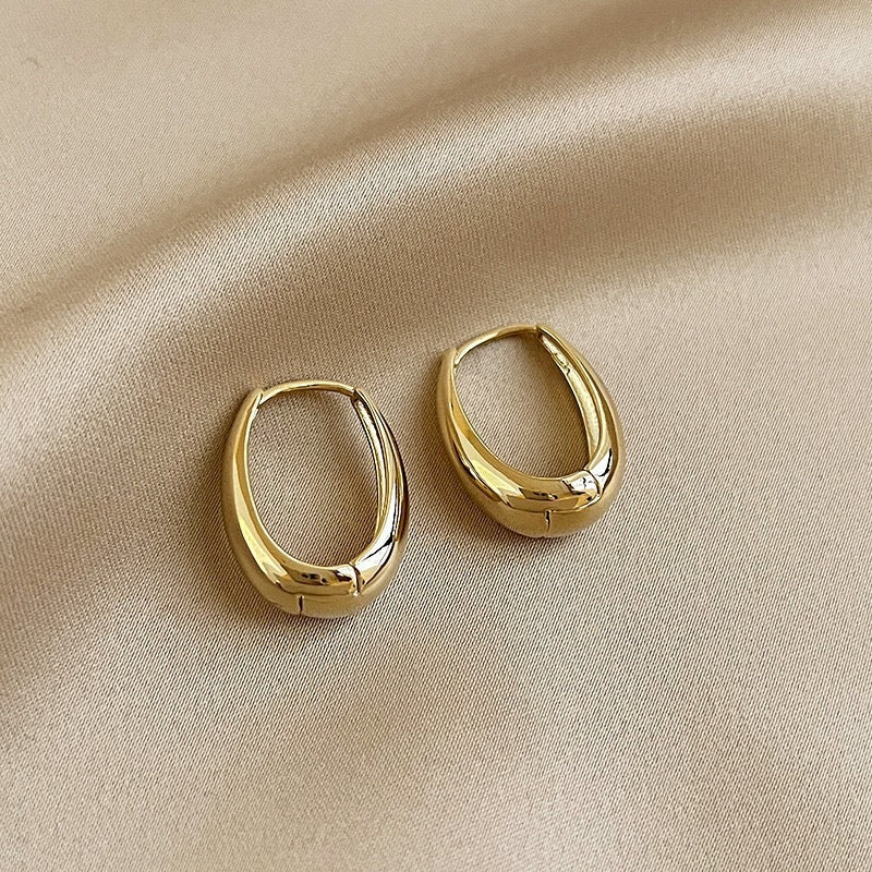 Pair of golden hoop earrings on beige satin fabric