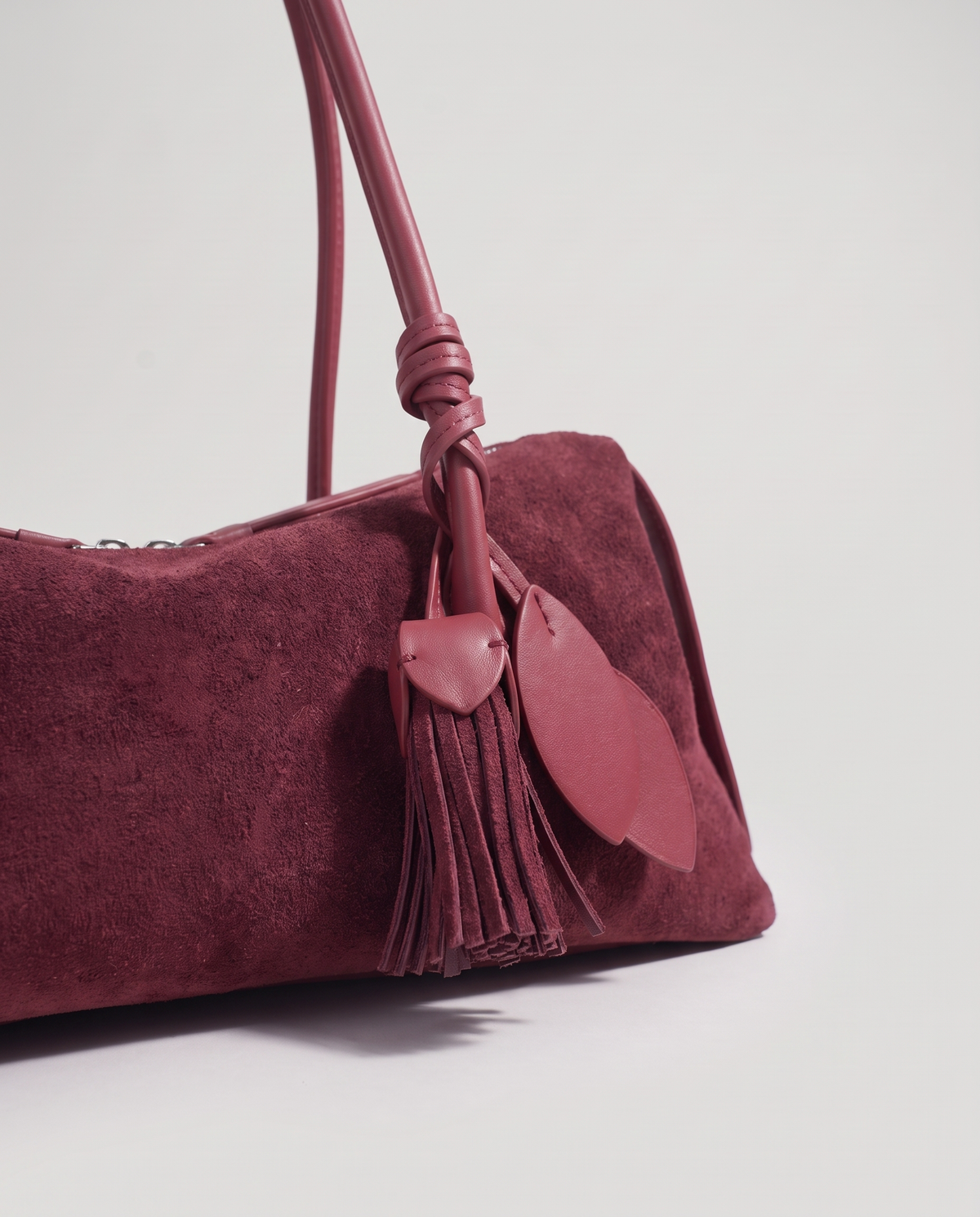 Isola suede shoulder bag in burgundy, leaf and tassel charm detail