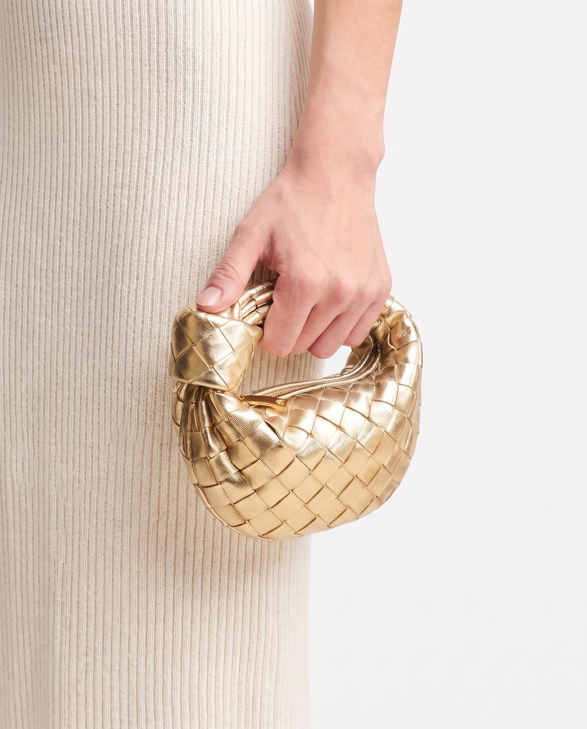 Knot Mini woven leather bag in Gold – held in the hand, showing true size