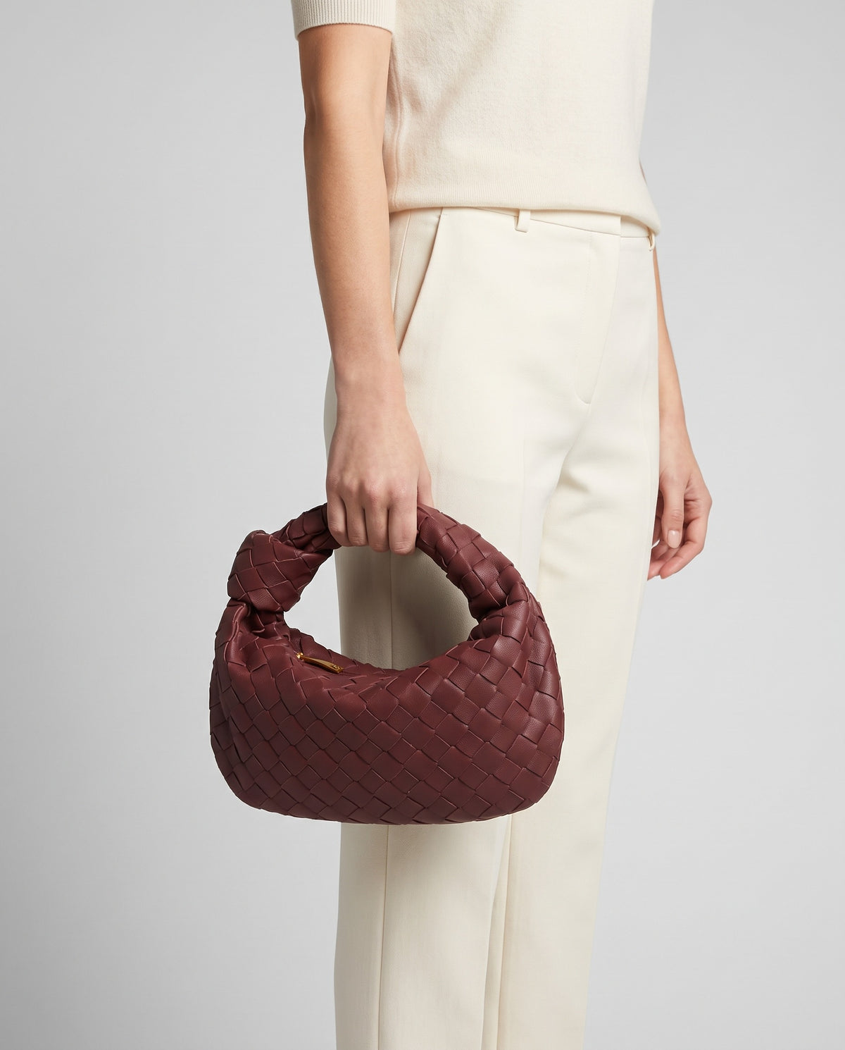 Knot Small woven leather bag in Bordeaux – model carrying it by the knotted handle