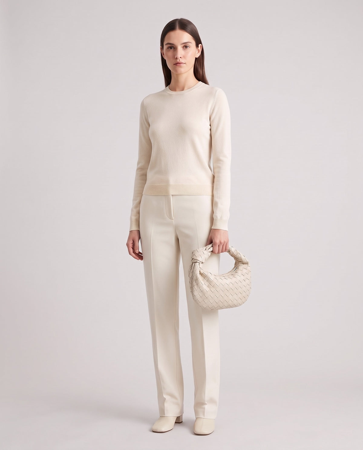 Model holding the Knot Small woven leather bag in Chalk – full length