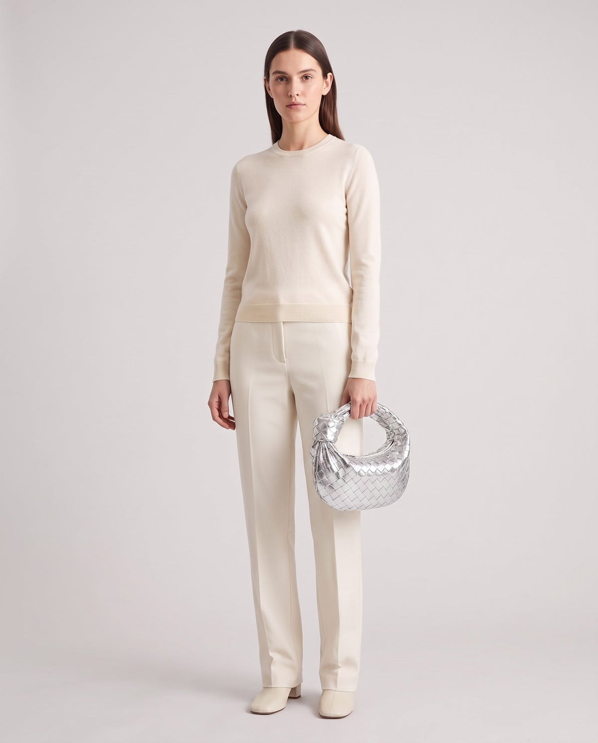 Model holding the Knot Small woven leather bag in Silver – full length